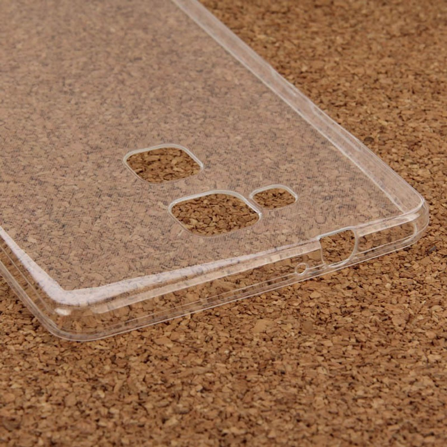 Transparente Handyhülle auf brauner Oberfläche, mit Löchern für Kamera und Anschlüsse.