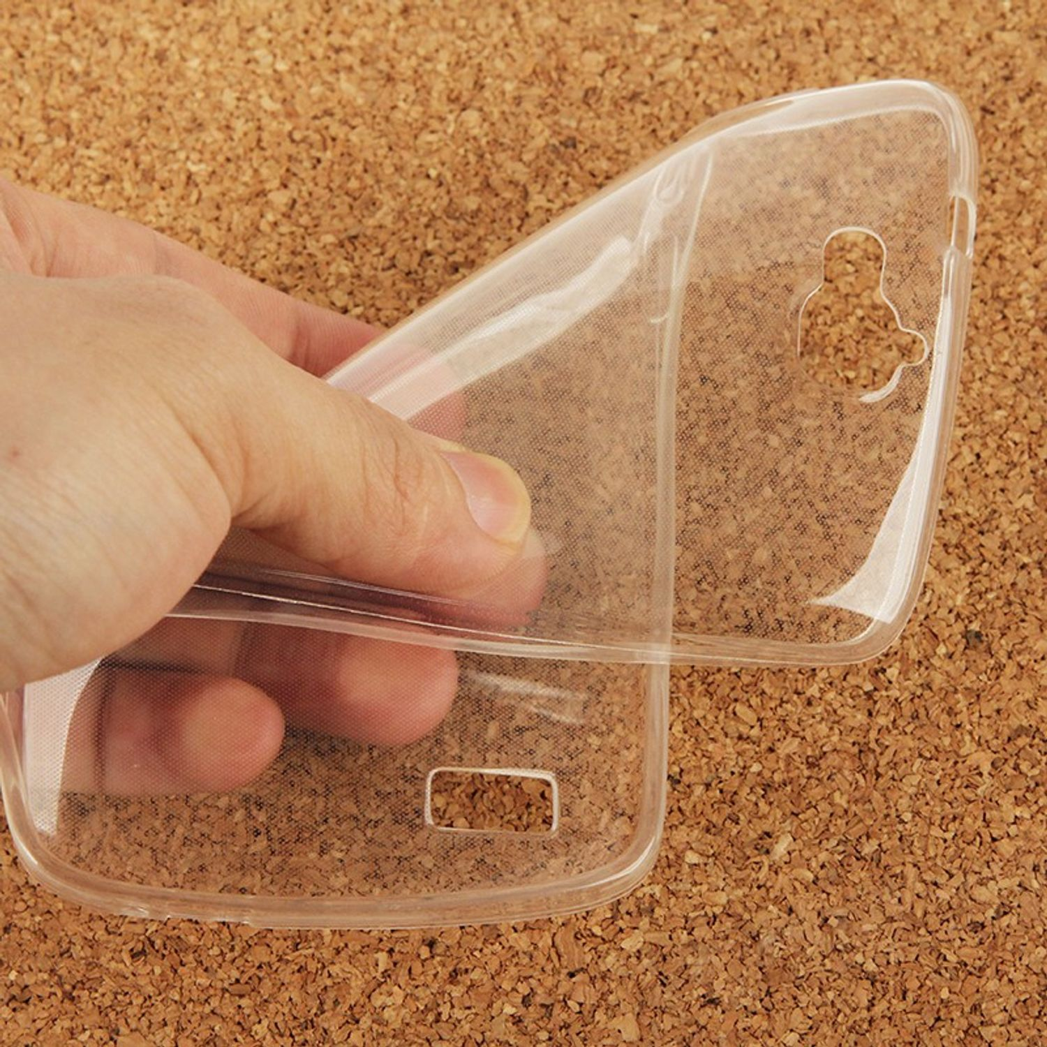 Eine Hand, die eine transparente Handyhülle über einer Korkoberfläche hält.