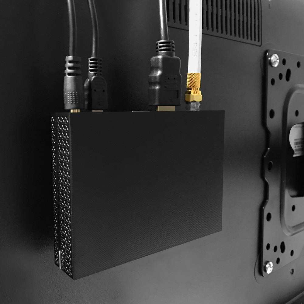 Schwarze Box mit angeschlossenen Kabeln, Rückansicht, vor schwarzer Wand.