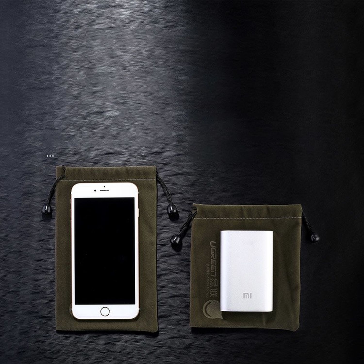 Due sacche verde oliva con coulisse. Una contiene uno smartphone bianco, l'altra un power bank argento.