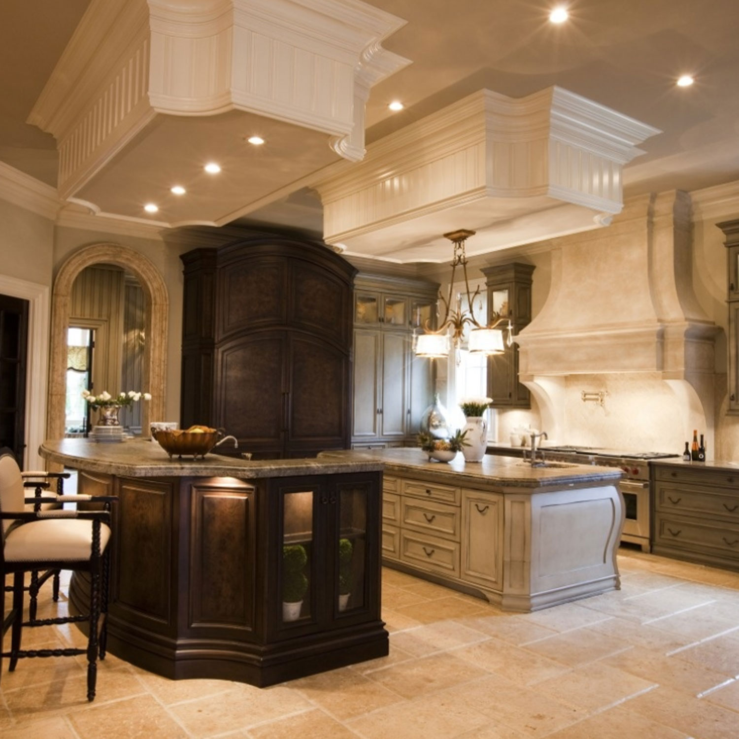 Una cucina di lusso con due isole, mobili in legno scuro e piani di lavoro beige.