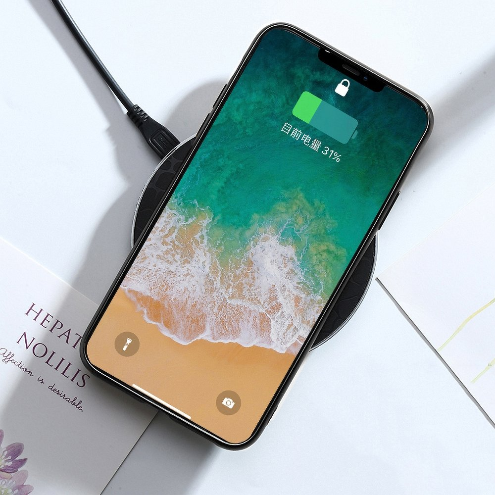 Telefon wird auf einem kabellosen Pad geladen. Telefon zeigt App und 31% Akku. Weißer Hintergrund.
