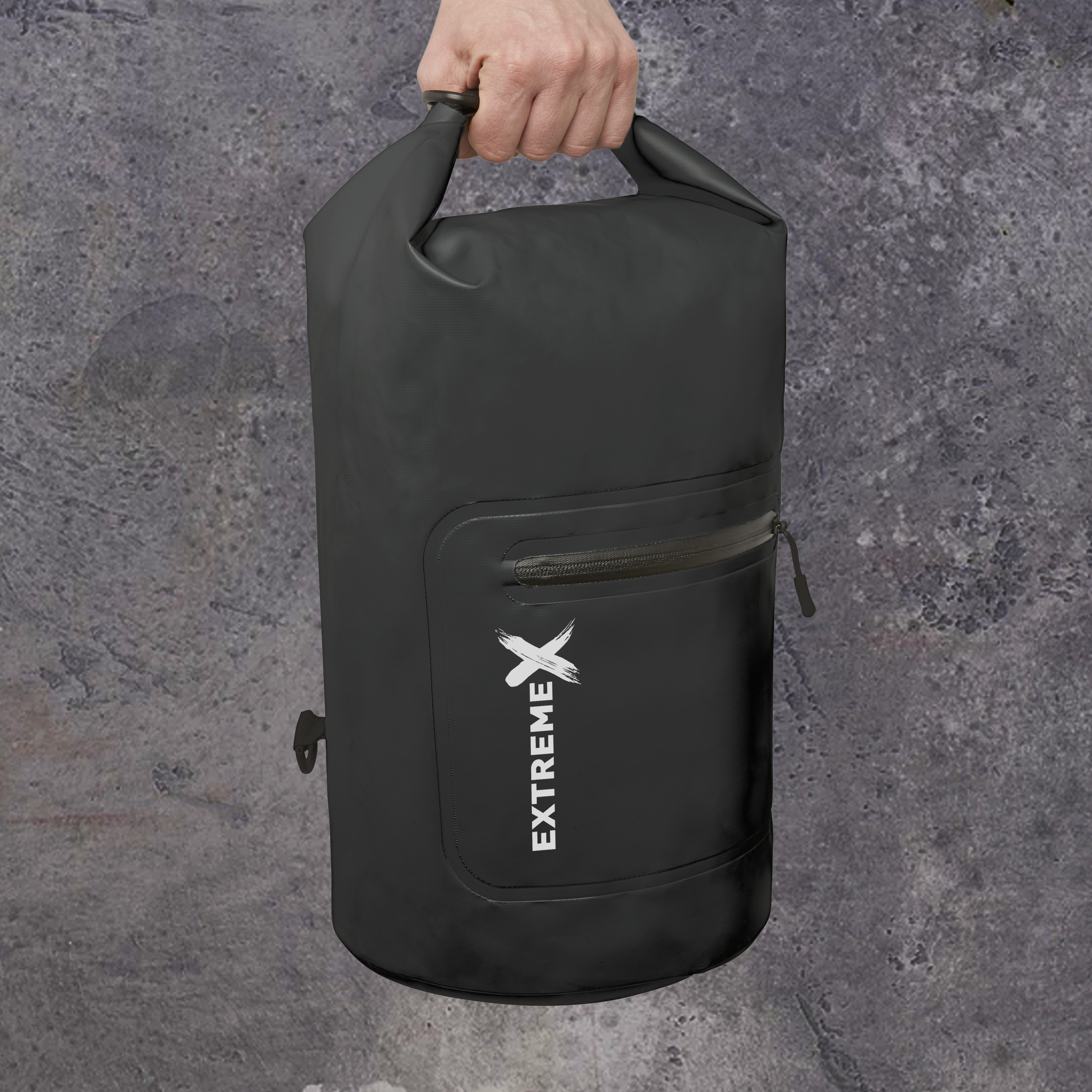 Schwarze wasserdichte Tasche, Extreme X Logo, Hand hält. Grauer, strukturierter Hintergrund.