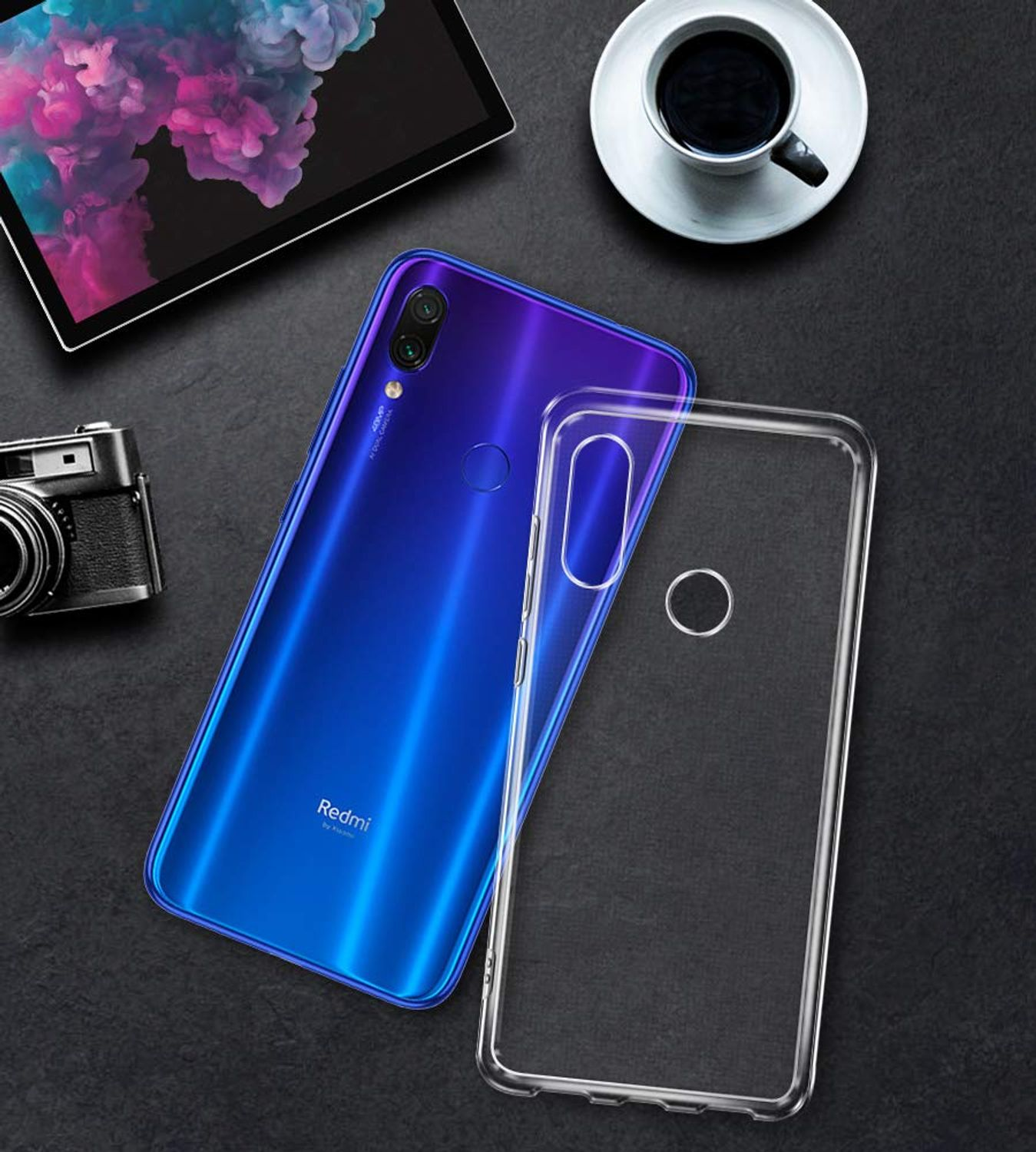 Blaues Telefon mit klarer Hülle neben einer schwarzen Oberfläche. Auf der Oberfläche befinden sich ein Tablet und eine Tasse.