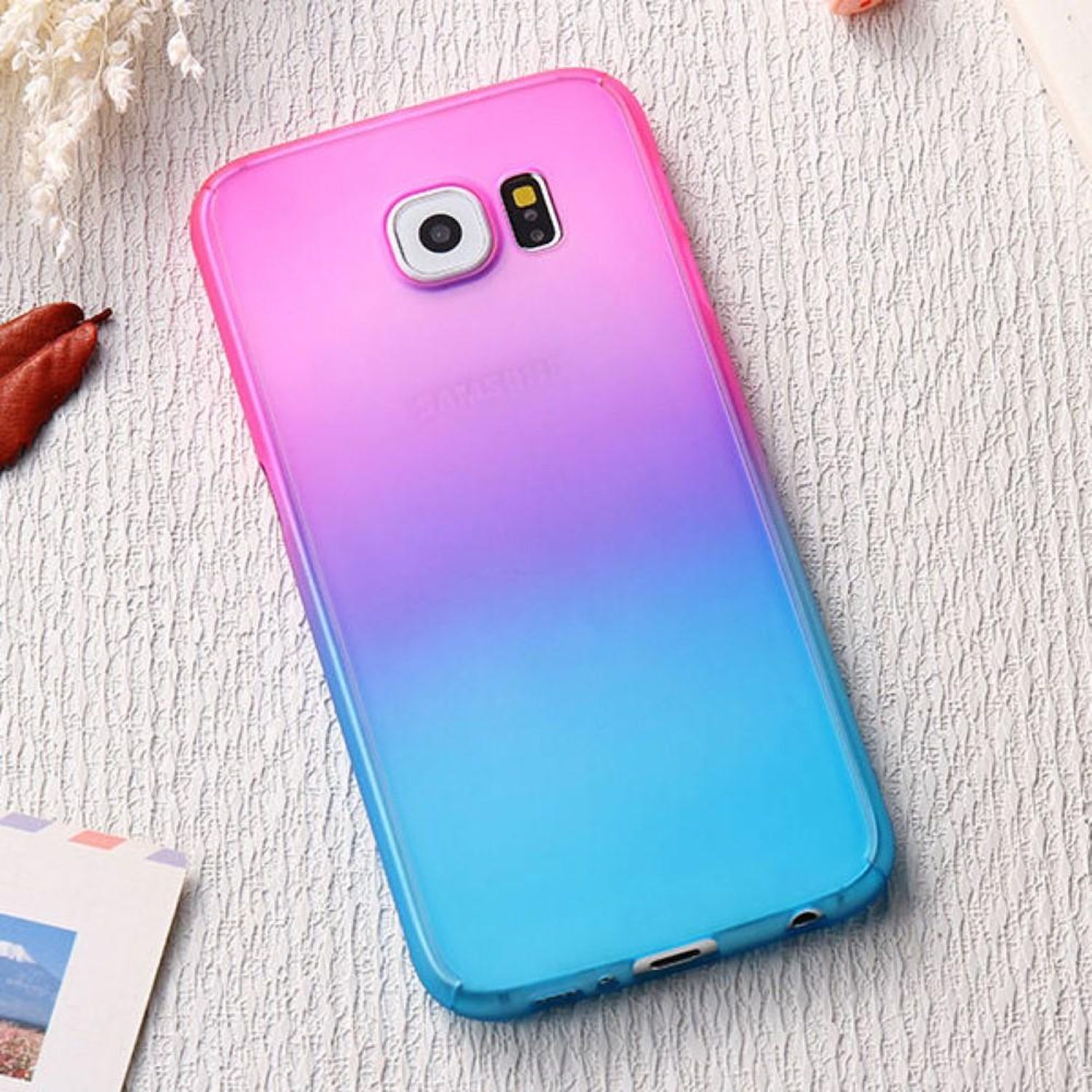 Eine Farbverlauf-Handyhülle mit blauen und rosa Farben, die ein Telefon bedeckt. Das Telefon liegt auf einer Oberfläche.