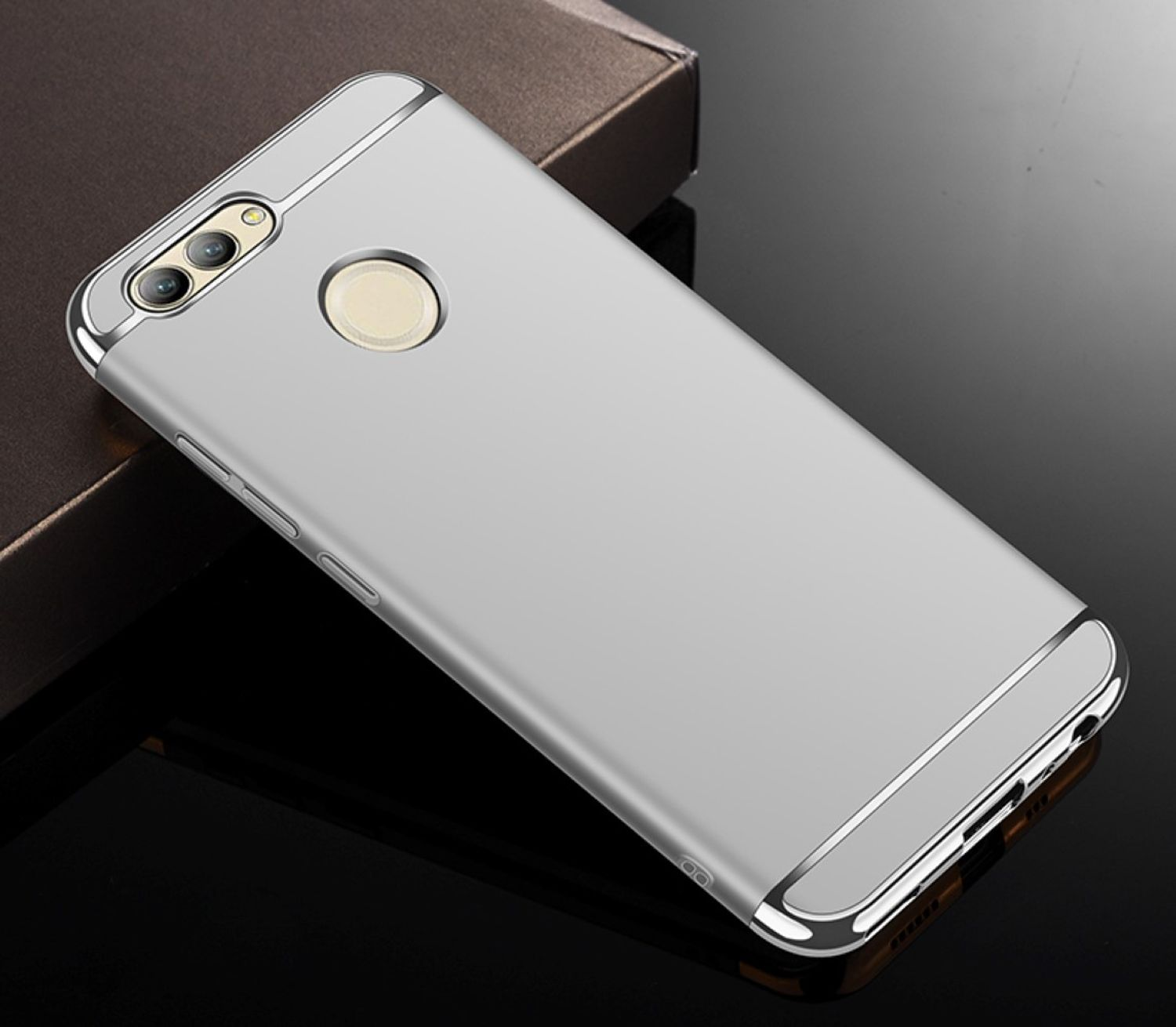 Eine silberne Handyhülle mit goldenem Kameraring liegt auf reflektierender Oberfläche.