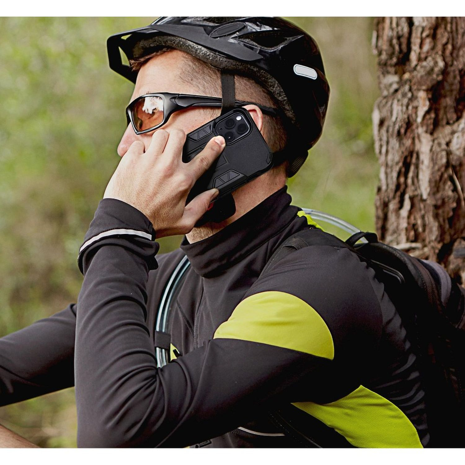 Mann telefoniert draußen, Helm und Sonnenbrille, schwarze Hülle am Telefon.