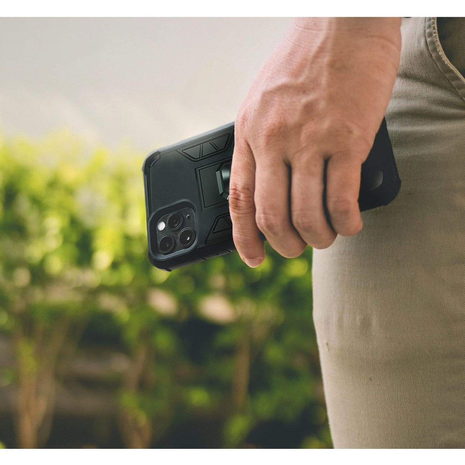 Eine Hand hält ein schwarzes Telefon mit schwarzer Hülle. Das Telefon hat einen Ständer.