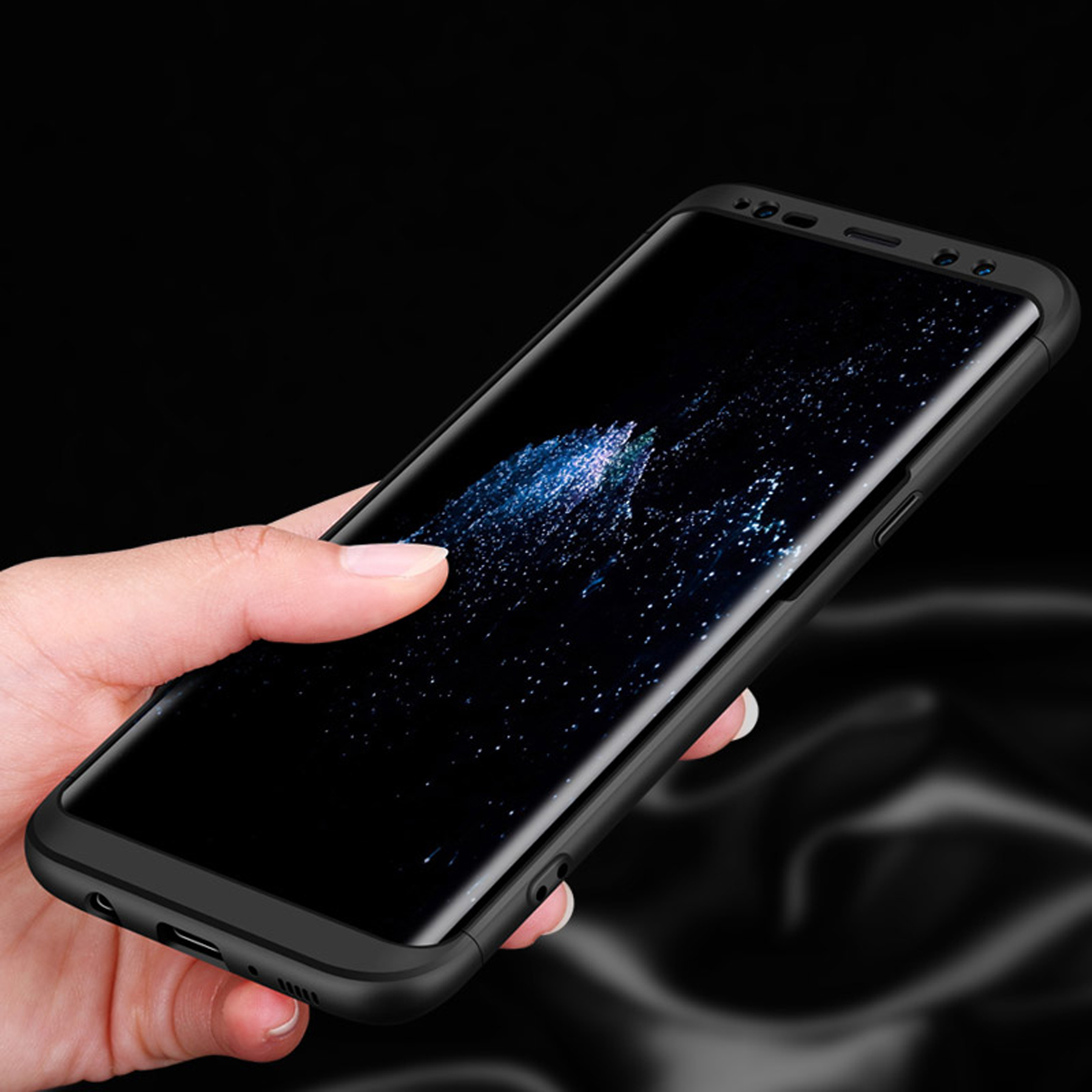 Eine Hand hält ein schwarzes Telefon in einer schwarzen Hülle. Der Bildschirm zeigt ein Galaxienbild.