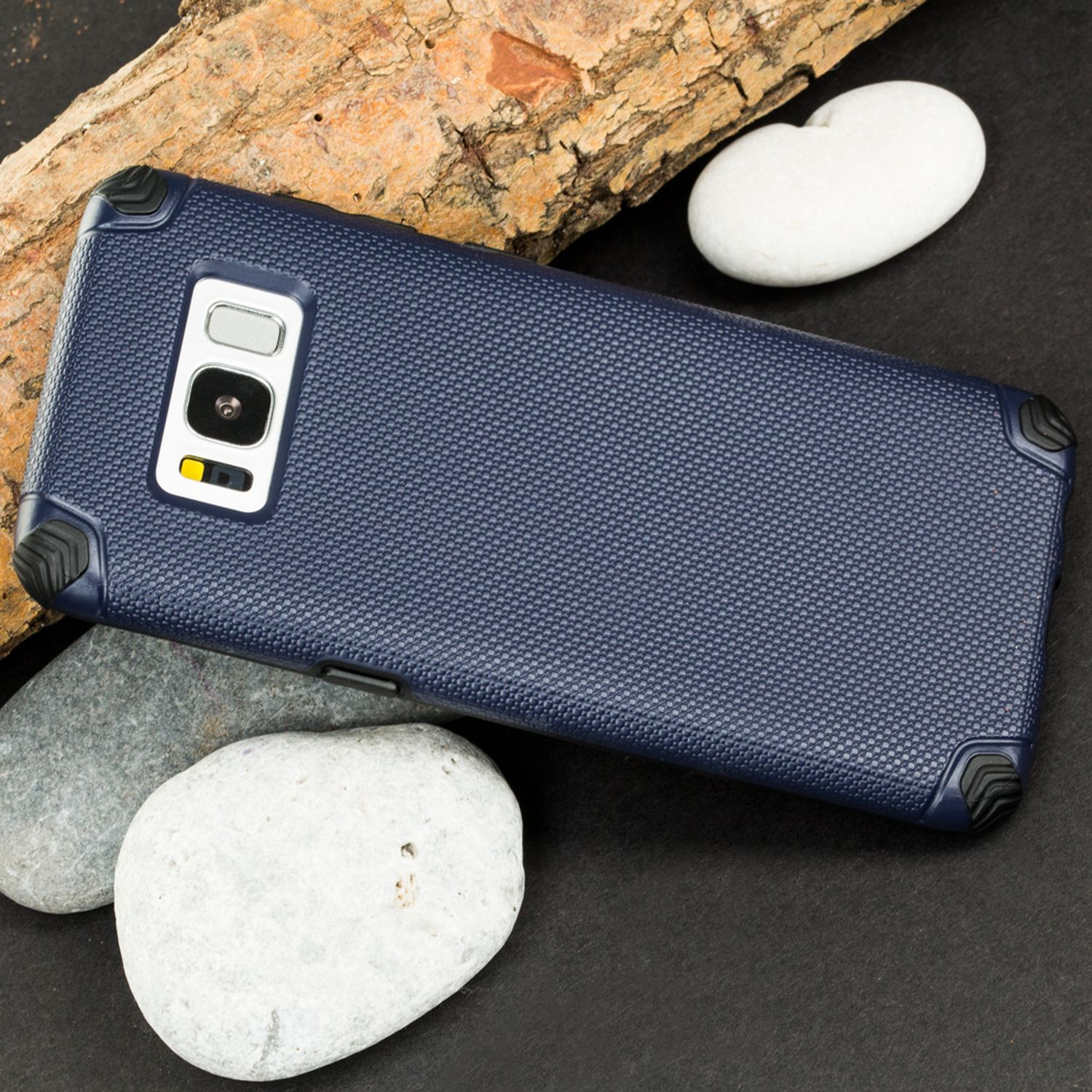 Una funda de teléfono azul oscuro con un diseño texturizado, sobre una superficie negra con piedras.