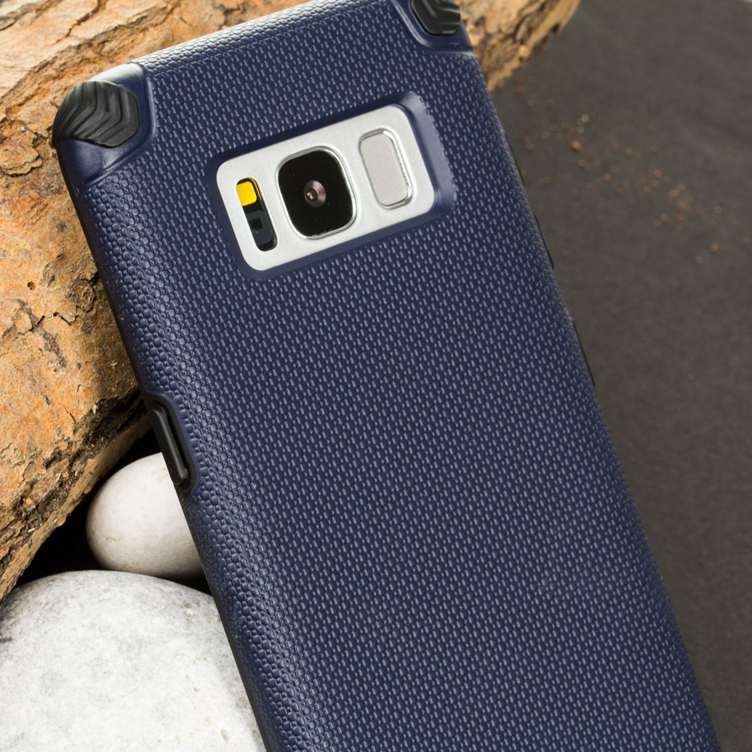 Funda de teléfono azul marino, primer plano en un tronco. Fondo oscuro.