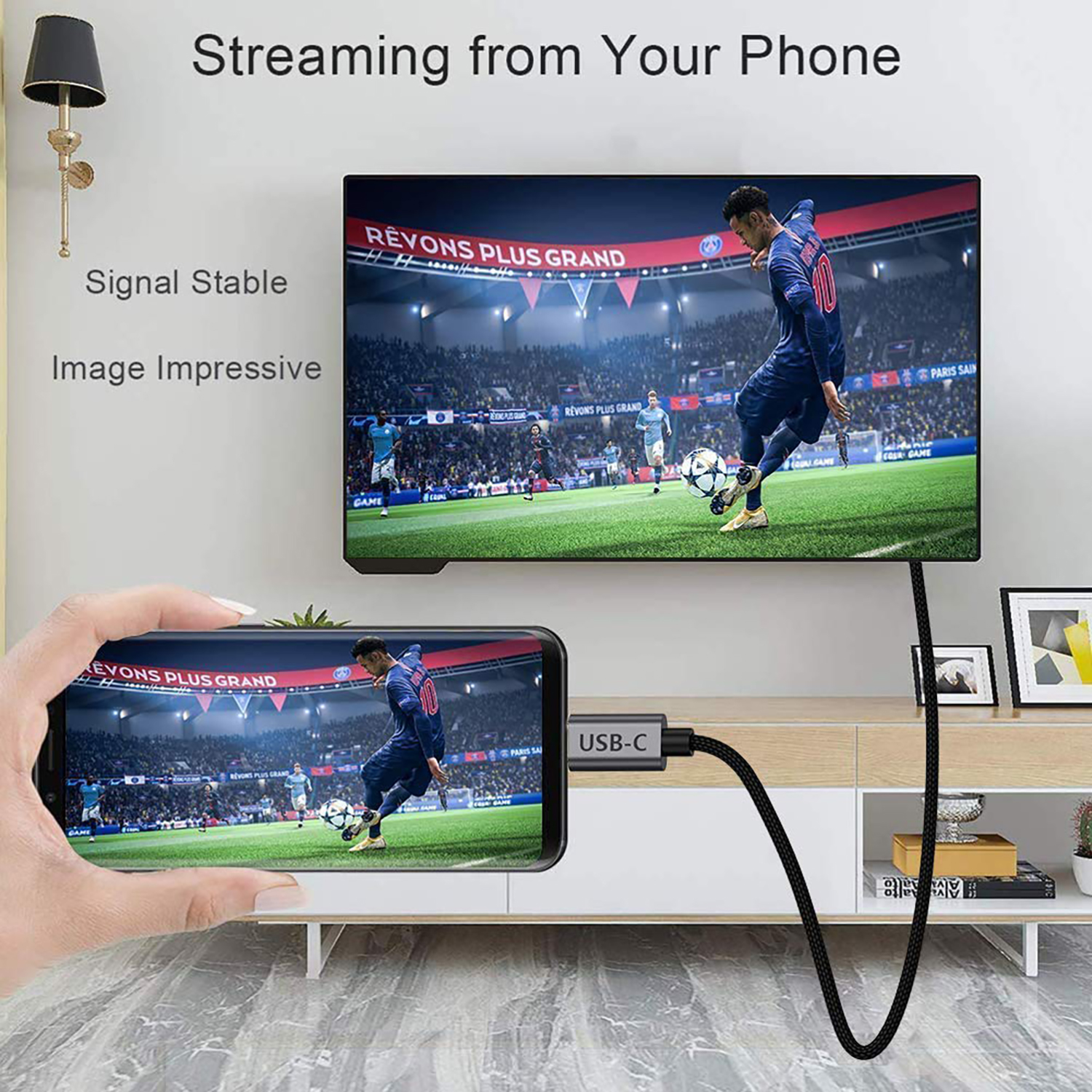 Eine Person hält ein Telefon, das ein Fußballspiel auf einen Fernseher streamt. Ein Kabel verbindet das Telefon mit dem Fernseher.