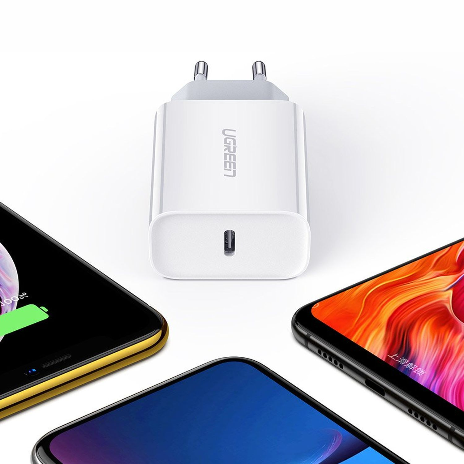Weißes USB-Ladegerät mit USB-C-Anschluss. Drei Telefone sind darum herum.
