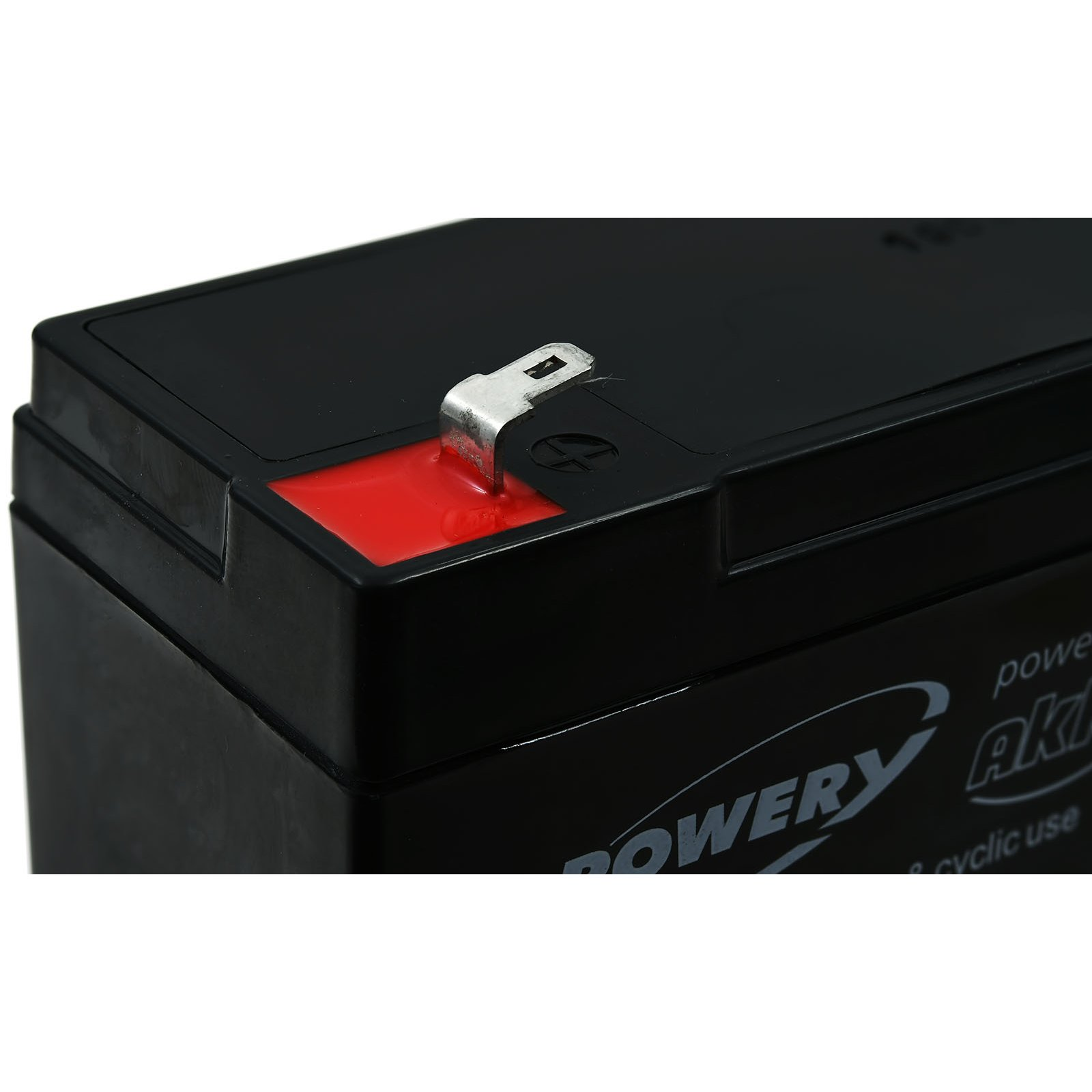 Una batería negra con conector metálico y parte superior roja, sobre fondo blanco.