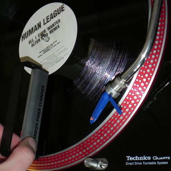 Plattenspieler mit schwarzer Vinyl-Schallplatte und Bürste zur Reinigung.
