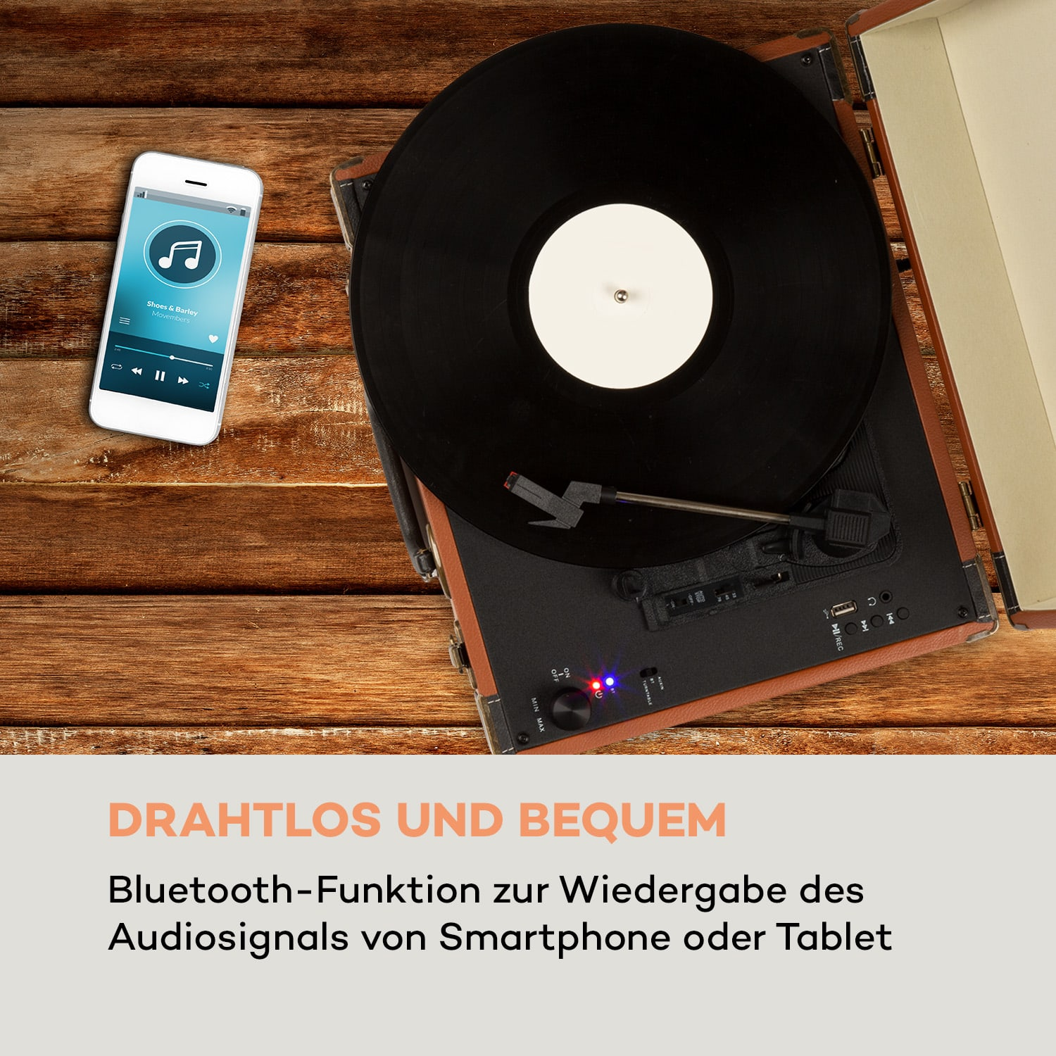 Plattenspieler mit Schallplatte und Smartphone. Es befindet sich auf einer Holzoberfläche.