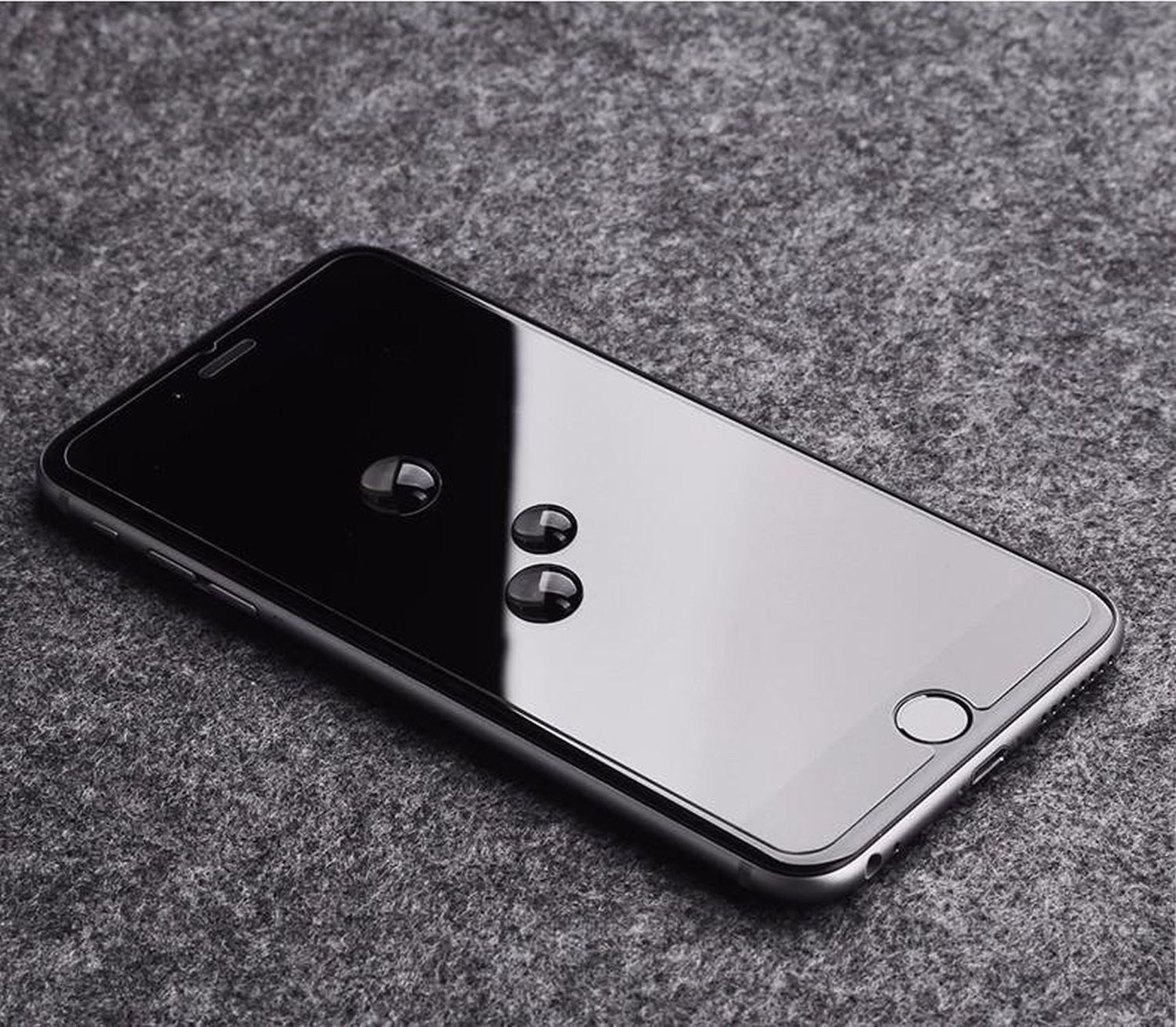 Ein Telefonbildschirm mit Wassertropfen. Grauer strukturierter Hintergrund.