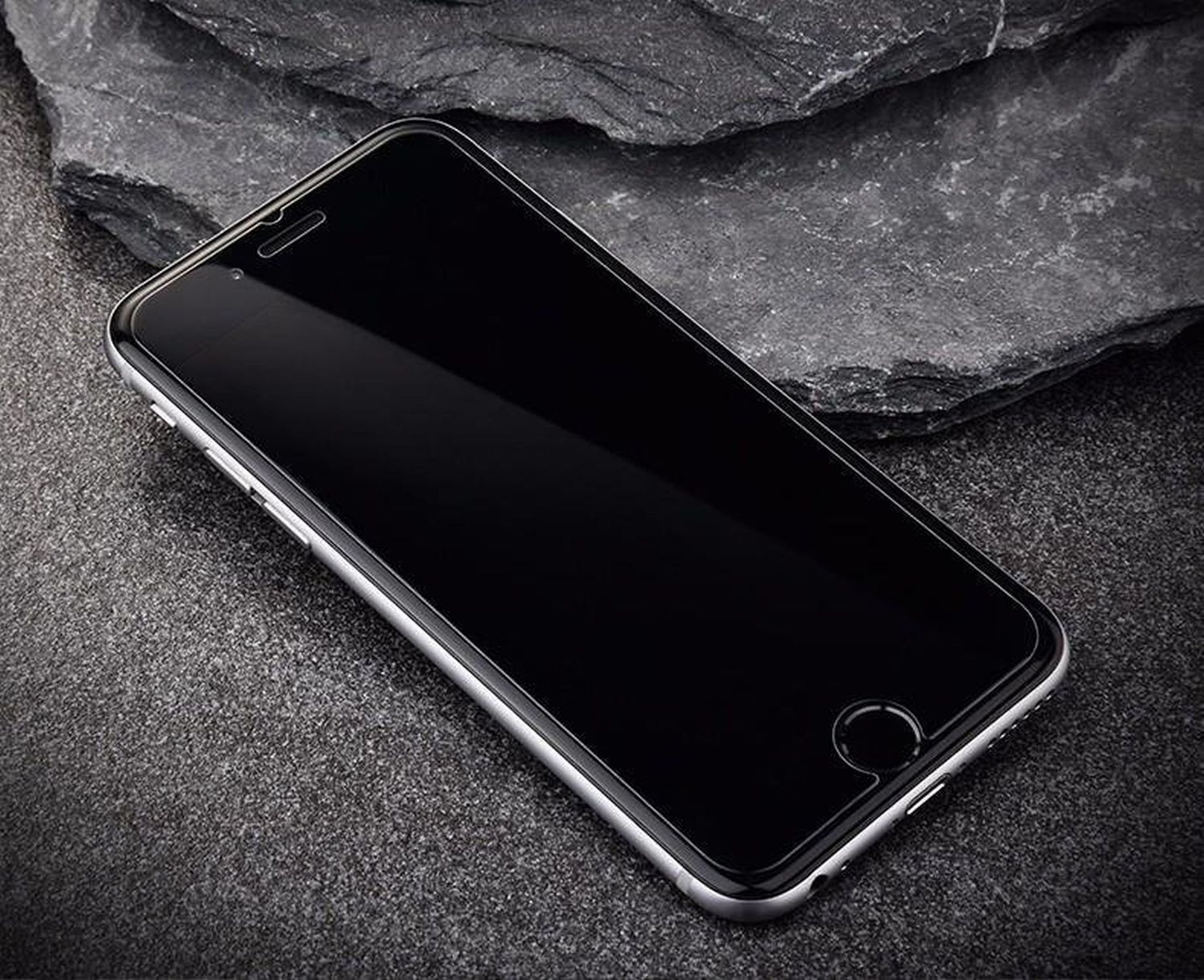 Schwarzes Telefon auf dunkler Steinoberfläche. Der Bildschirm ist leer. Dunkler Hintergrund.