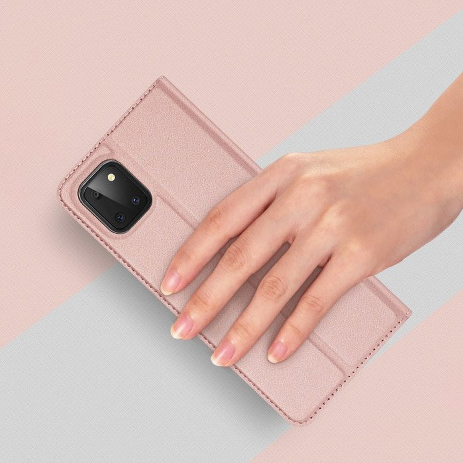 Eine Hand hält eine pinke Handyhülle. Die Hülle ist offen. Der Hintergrund hat ein rosa und graues Farbschema.