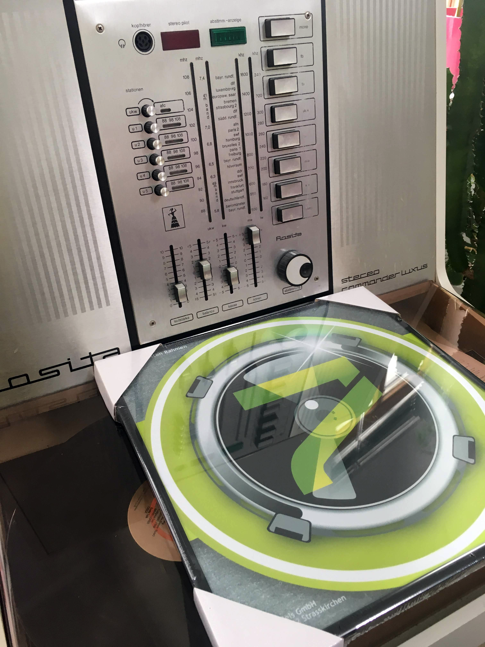 Ein Vintage-Stereo mit Knöpfen und Schiebereglern, ein gerahmtes Album und eine Schallplatte.