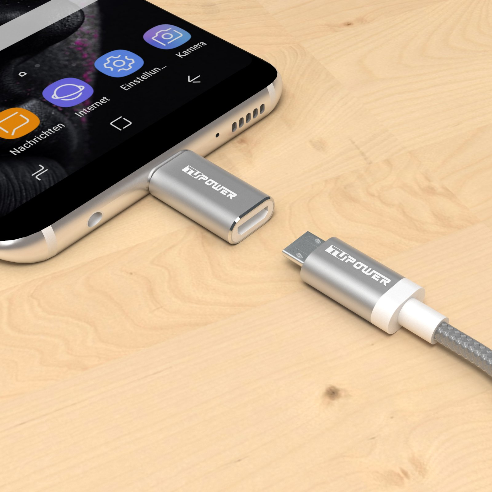 Telefon mit silbernem Adapter und grauem Kabel auf Holzoberfläche verbunden.