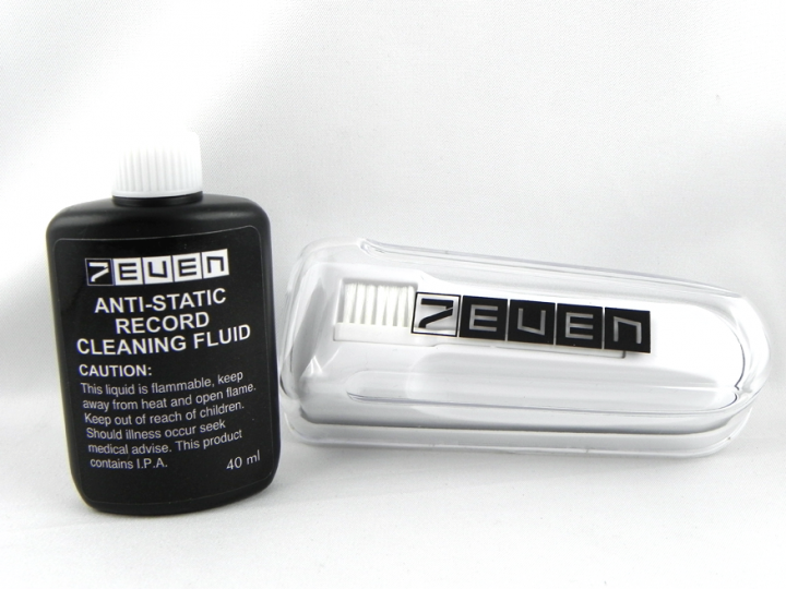 Schwarze Flasche Plattenreinigungsflüssigkeit und eine Bürste in einem durchsichtigen Etui, auf weißer Oberfläche.