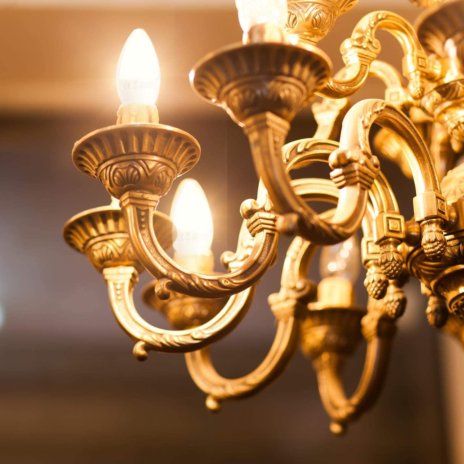 Un lampadario dorato con lampadine a candela accese brilla dolcemente.