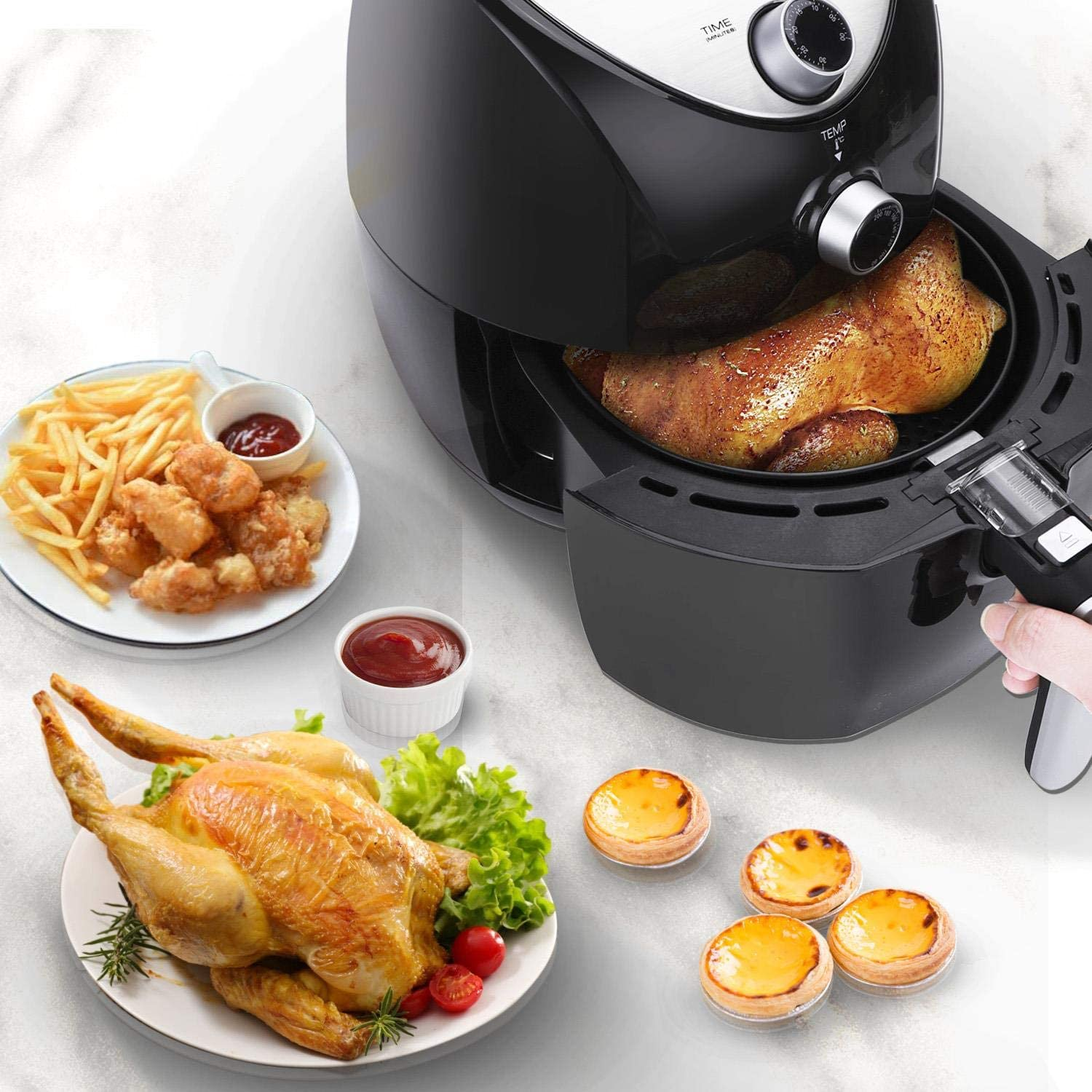 Una friggitrice ad aria con pollo arrosto, patatine fritte e pasticcini. Anche, un intero pollo arrosto e condimenti.