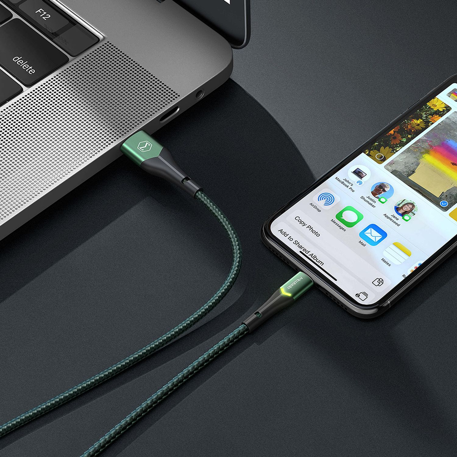 Ein Laptop, der über ein grünes Ladekabel mit einem Telefon verbunden ist.
