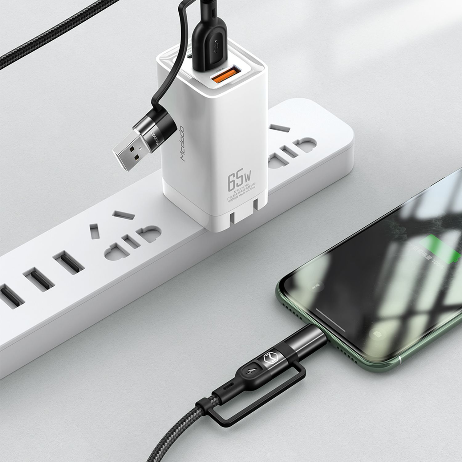 Bir güç adaptörü ve bağlı bir şarj kablosu olan bir telefon. Adaptör 65W diyor.