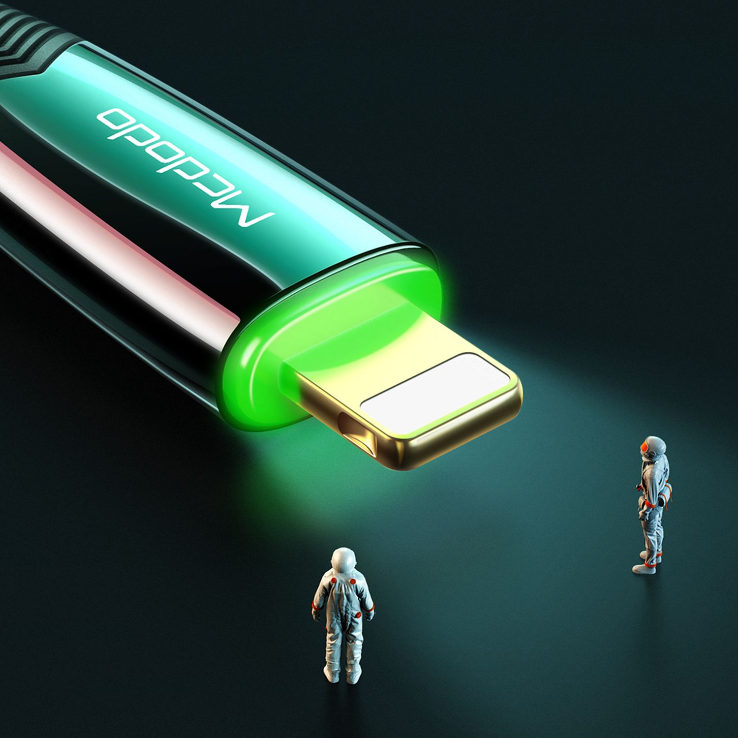 Ein Ladekabel mit goldfarbenem Stecker, der grün leuchtet, und zwei Spielzeug-Astronauten.