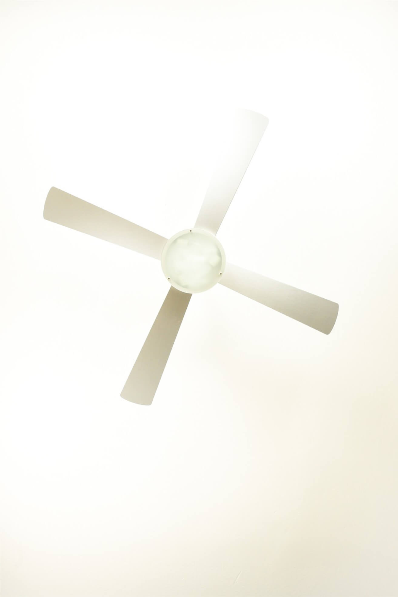 Un ventilatore da soffitto bianco con quattro pale. Le pale sono angolate. Il centro è una forma circolare bianca.