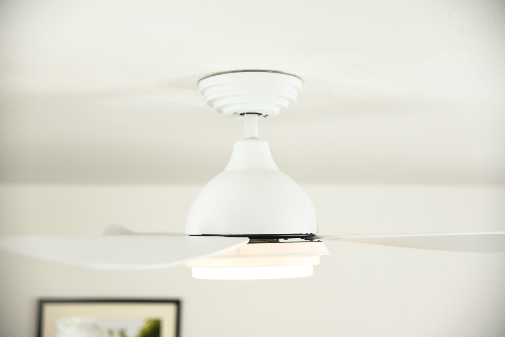 Weißer Deckenventilator mit drei Flügeln und einer Leuchte.