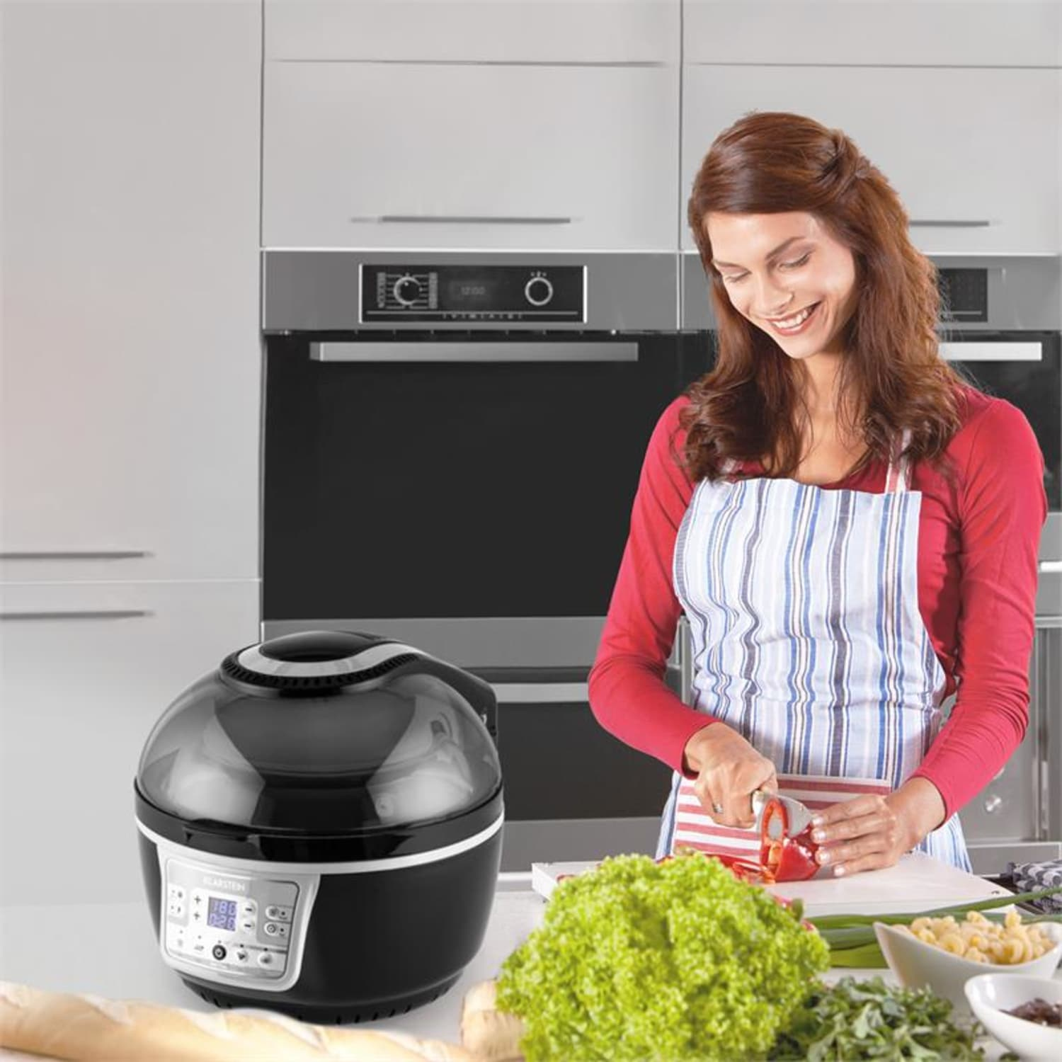 Donna in cucina che taglia verdure accanto a una friggitrice ad aria nera. Sfondo cucina.