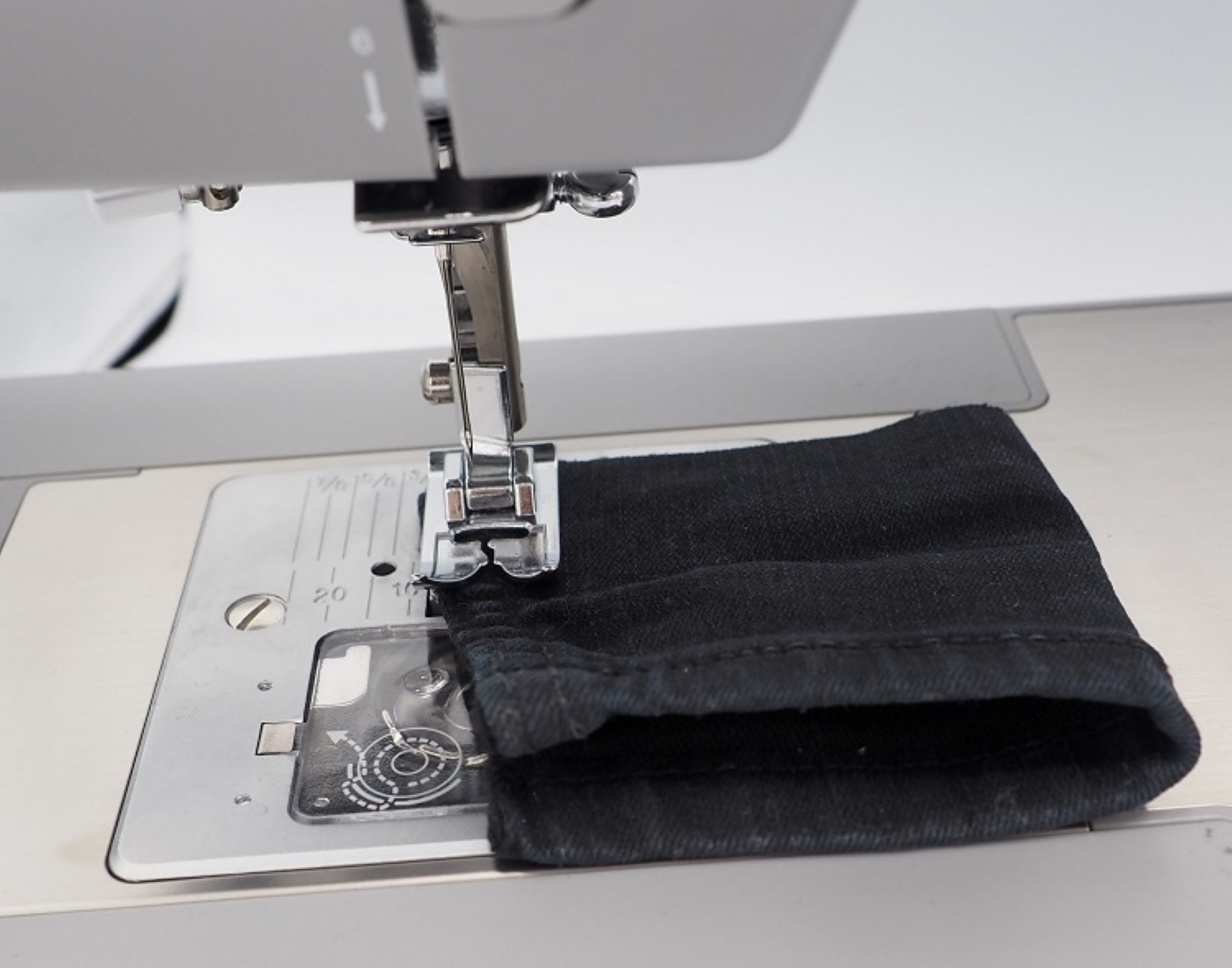 Maszyna do szycia szyjąca czarną tkaninę. Igła przebija materiał.