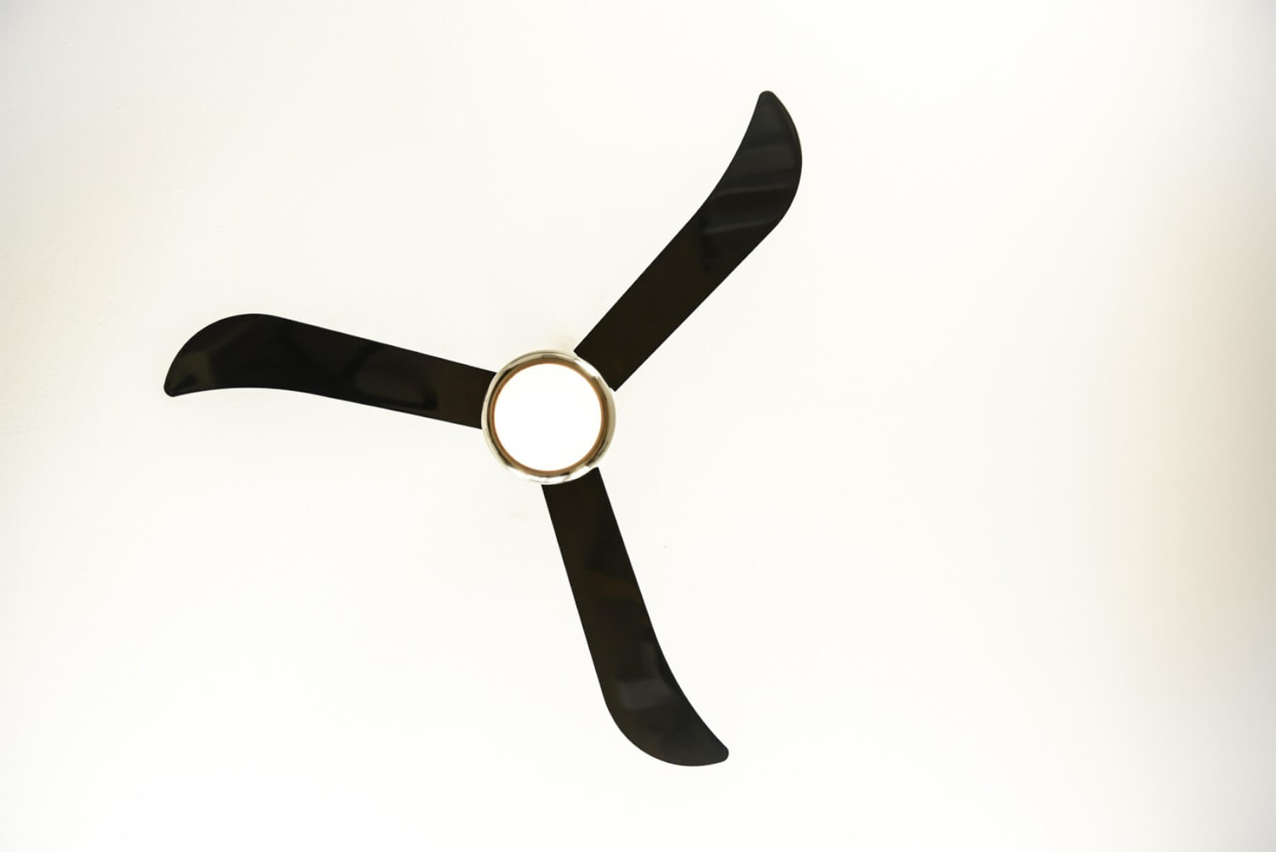 Ein Deckenventilator mit drei schwarzen Flügeln und einem silbernen Mittelring vor weißem Hintergrund.