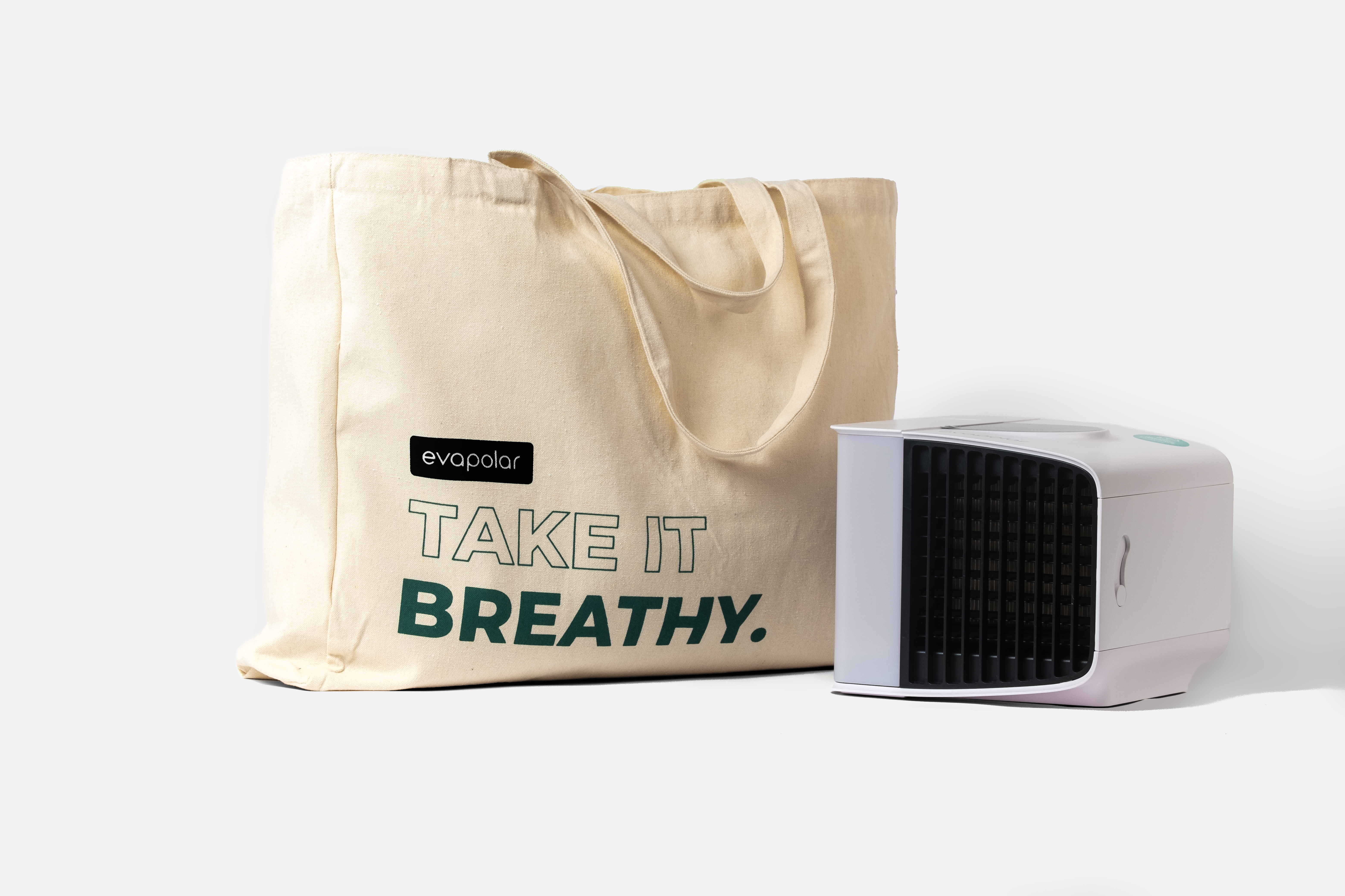 Ein weißer tragbarer Klimaanlage mit einer beigen Tragetasche. Die Tasche hat den Text "TAKE IT BREATHY".