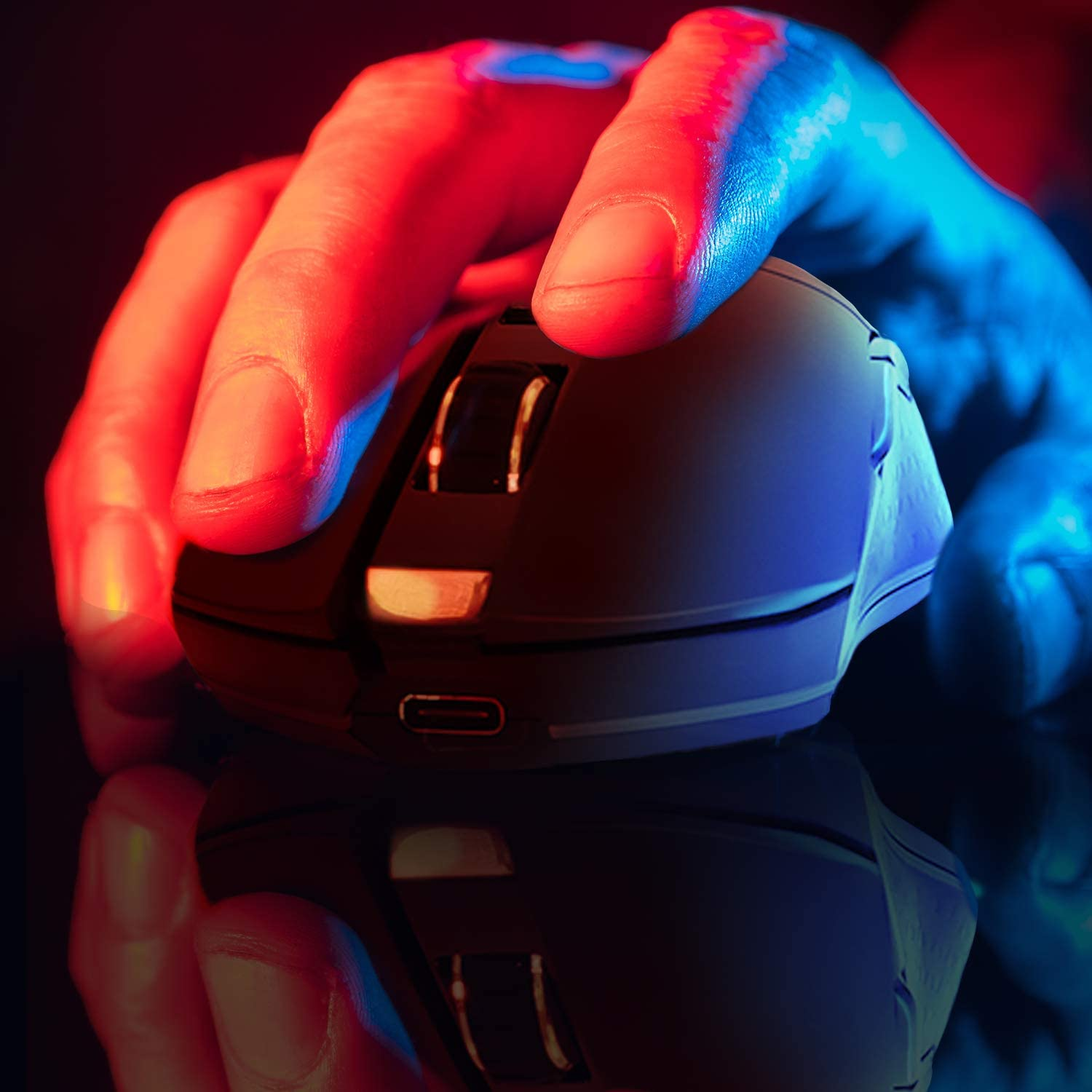 Hand, die eine schwarze Computermaus unter rotem und blauem Licht hält.