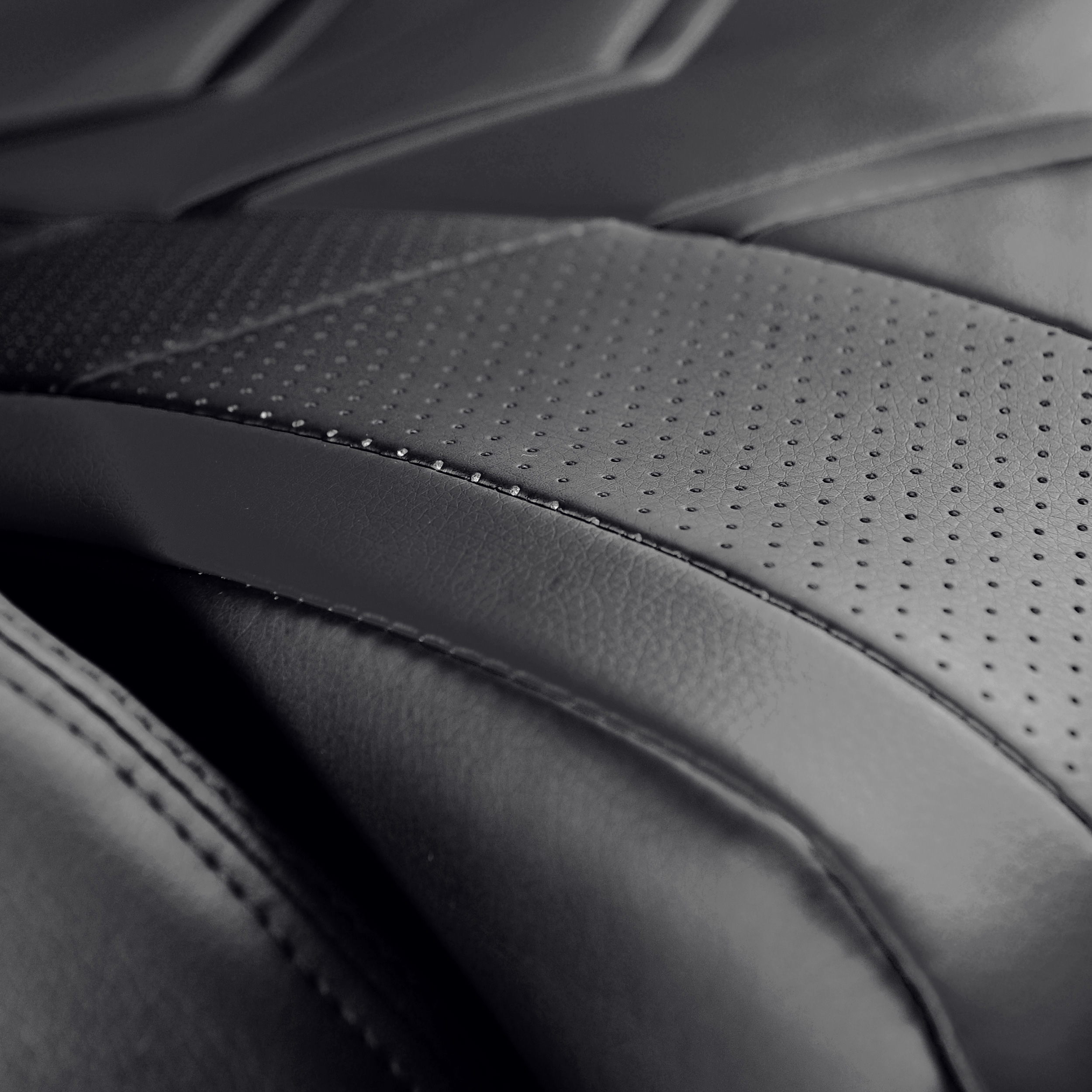 Zbliżenie czarnego skórzanego krzesła z perforowanymi i pełnymi sekcjami.