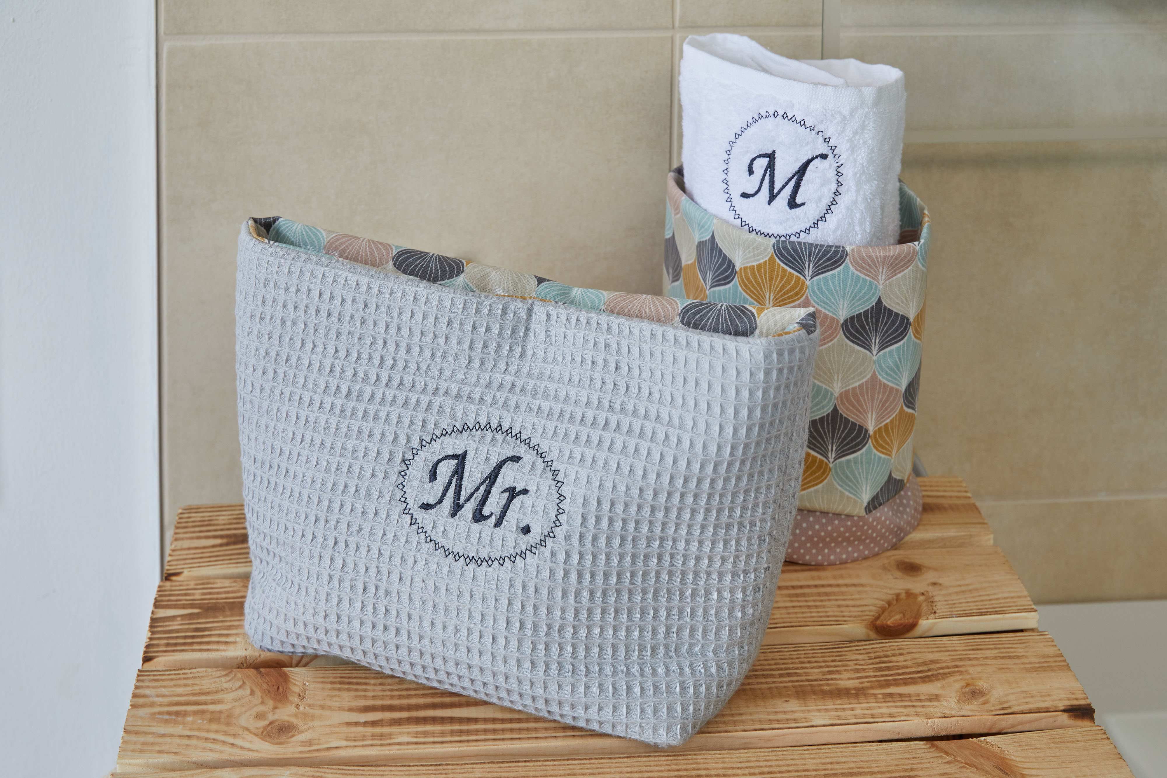 Borsa grigia a trama waffle con logo Mr., asciugamani e un contenitore decorato.
