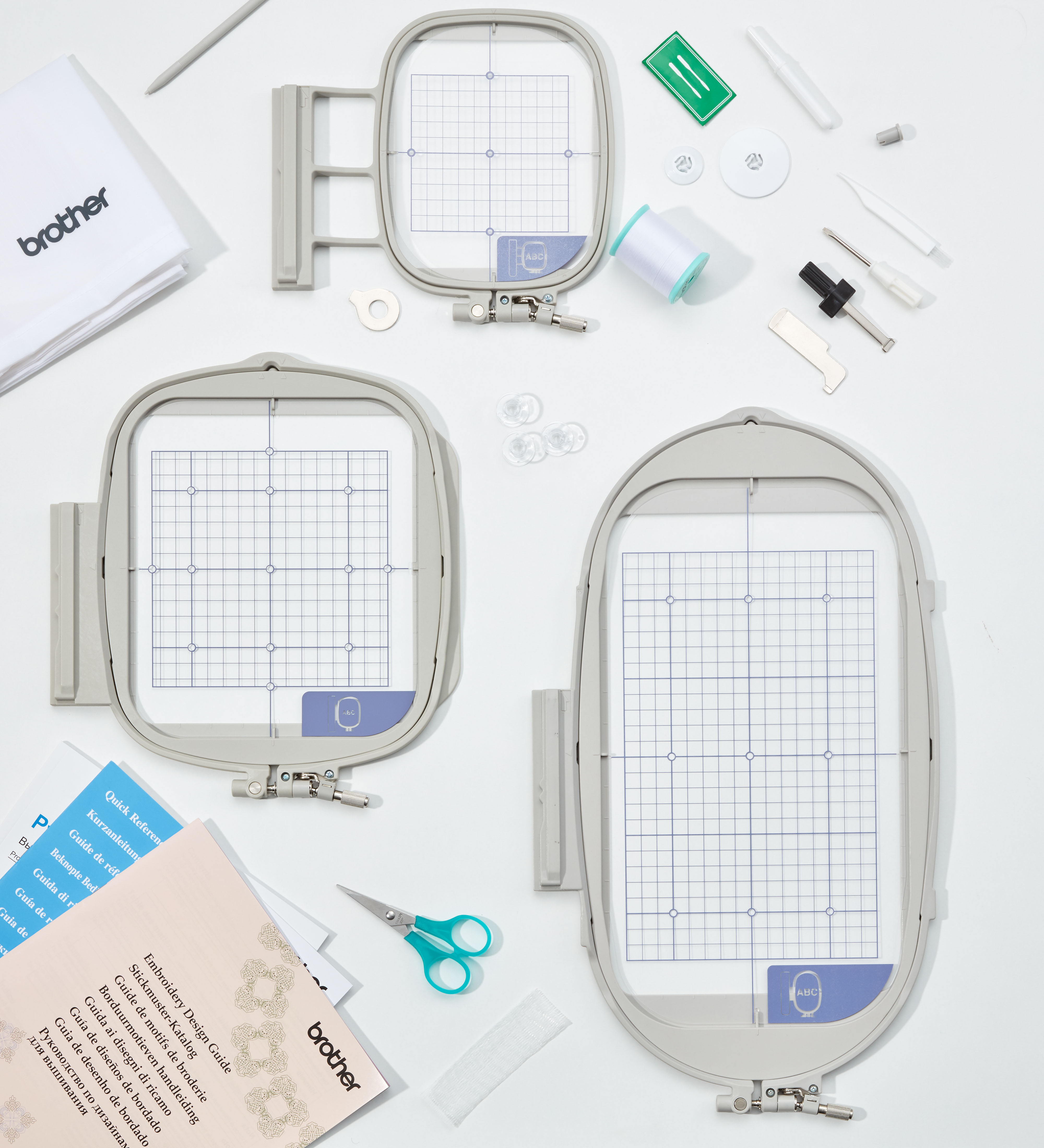 Telai da ricamo e accessori su una superficie bianca, con testo e forbici.