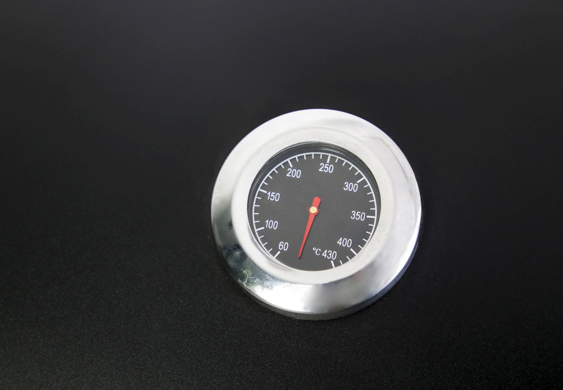Ein schwarzes Grillthermometer mit silberner Lünette, das die Temperatur anzeigt.