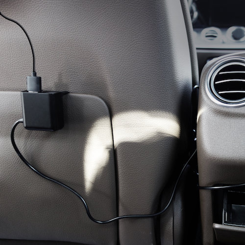 Autoladegerät im Auto angeschlossen, mit schwarzem Ladegerät und schwarzem Kabel.
