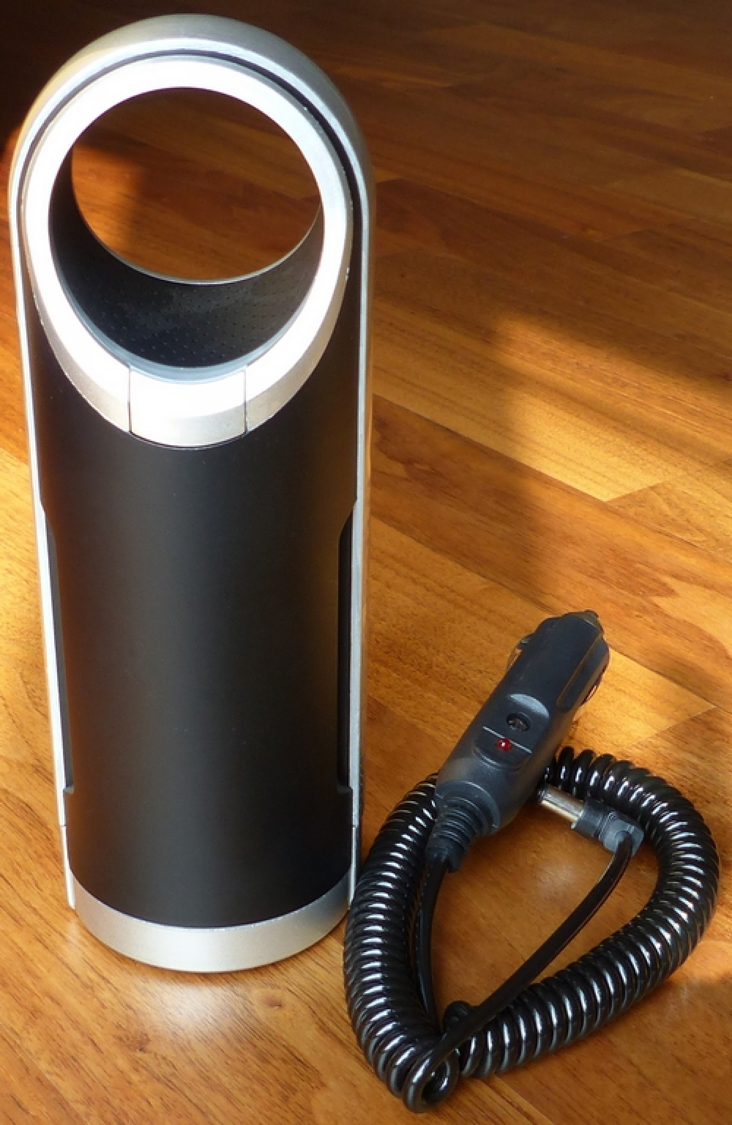 Schwarzer und silberner Luftreiniger mit schwarzem Netzkabel und schwarzem Adapter.