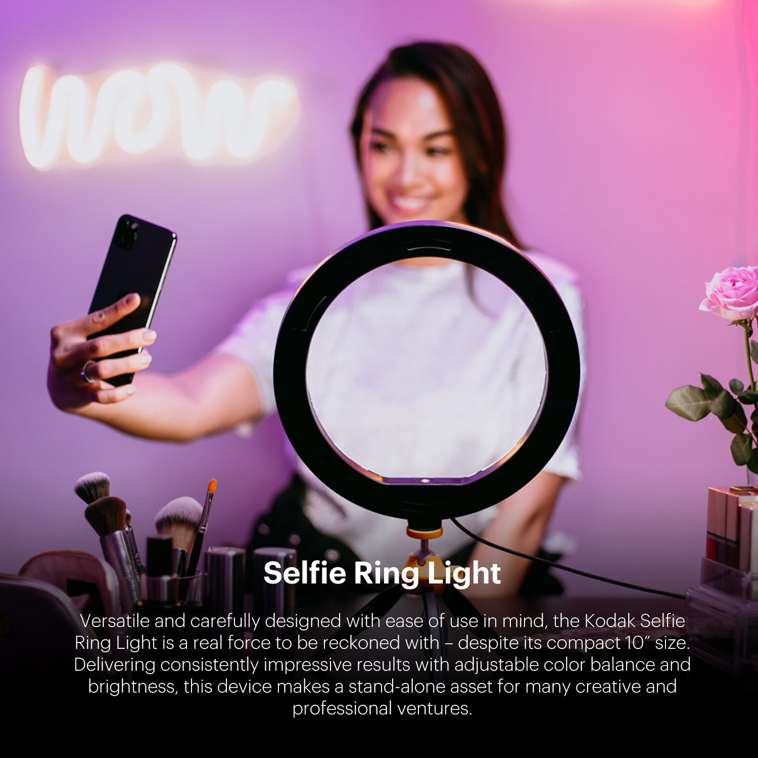 Una donna tiene un telefono con luce ad anello e pennelli per il trucco. Un cartello dice 'wow'.