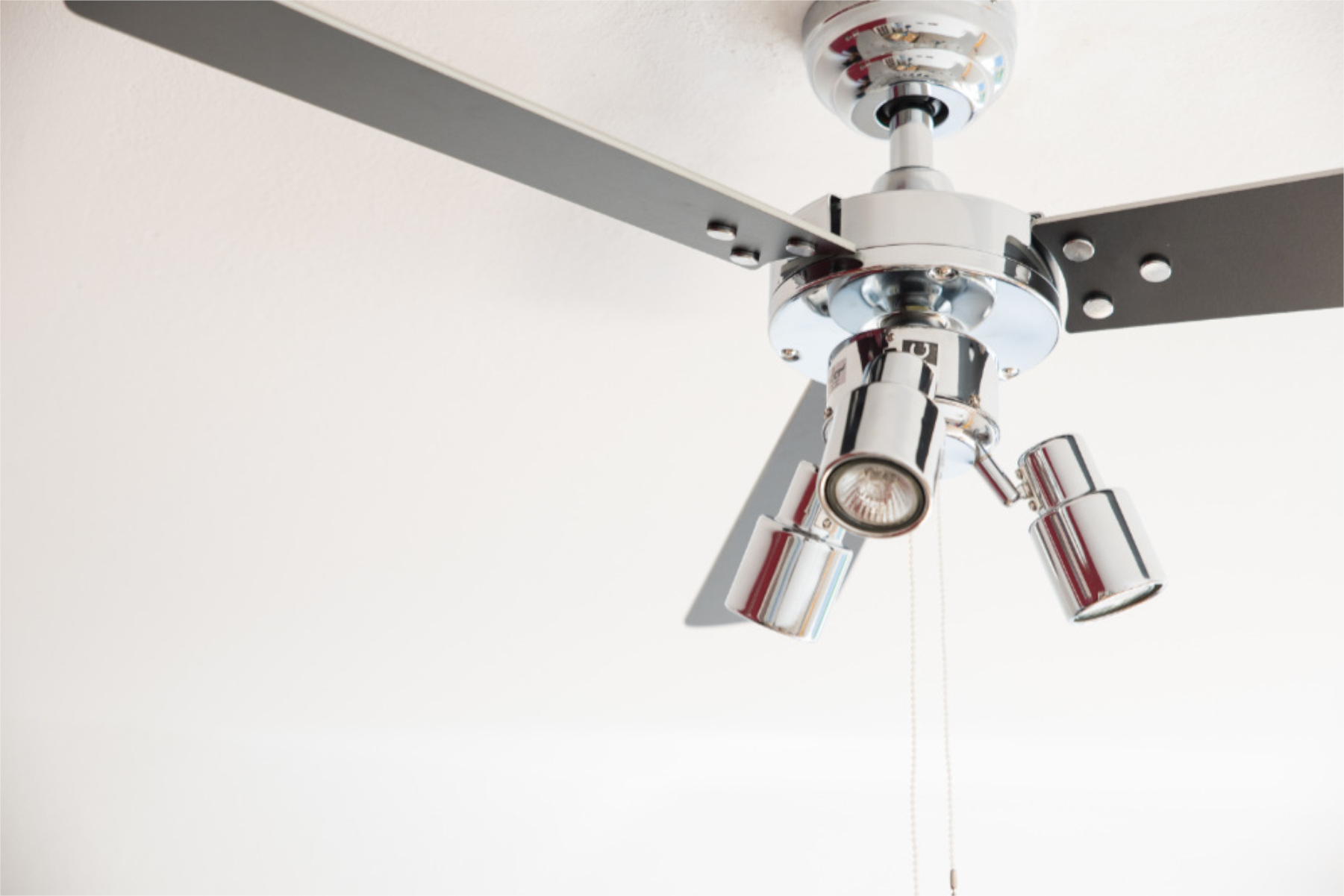 Deckenventilator mit Lichtern, Chrom-Finish, an einer weißen Decke.