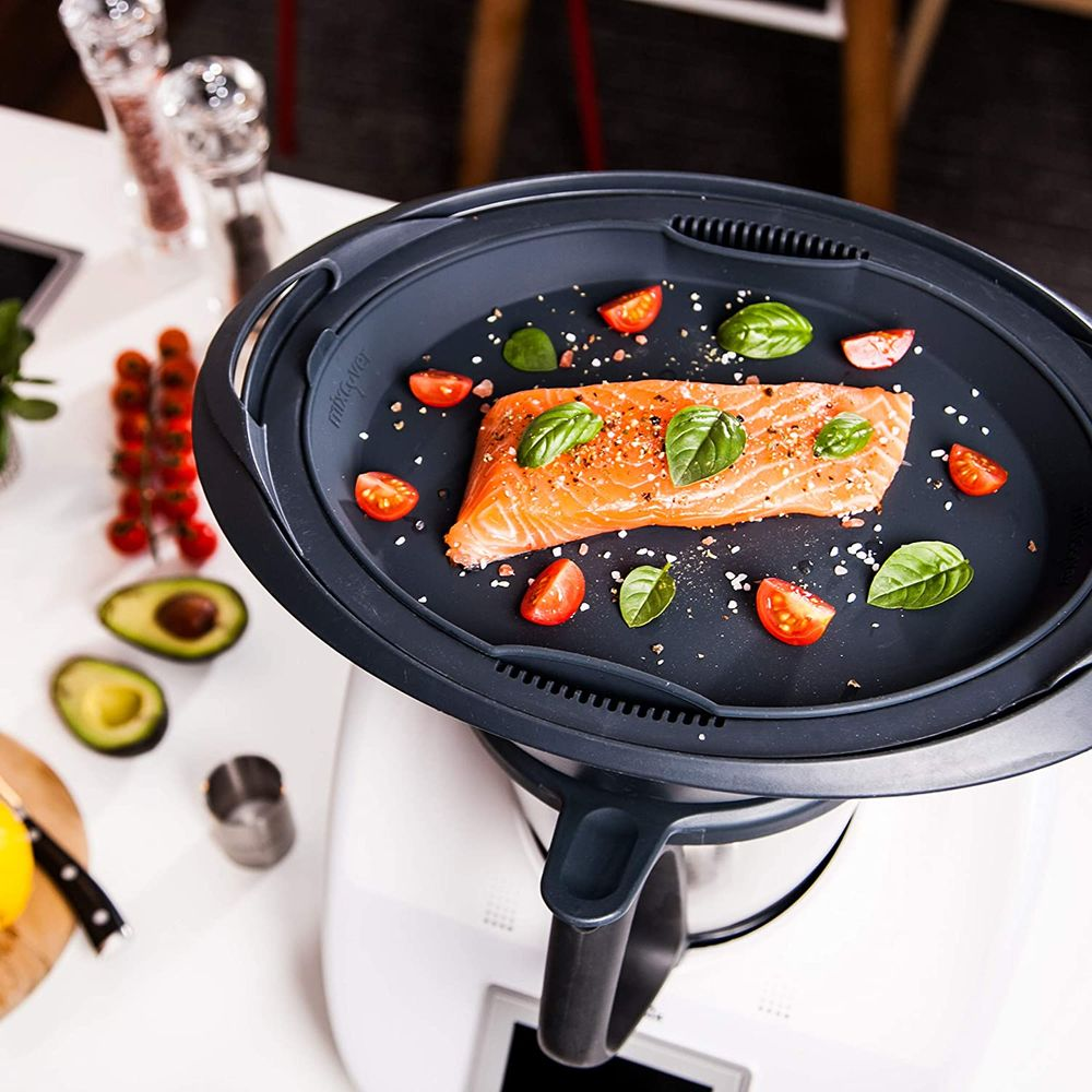 Lachs mit Tomaten und Basilikum auf einem Tablett über einer weißen Maschine.