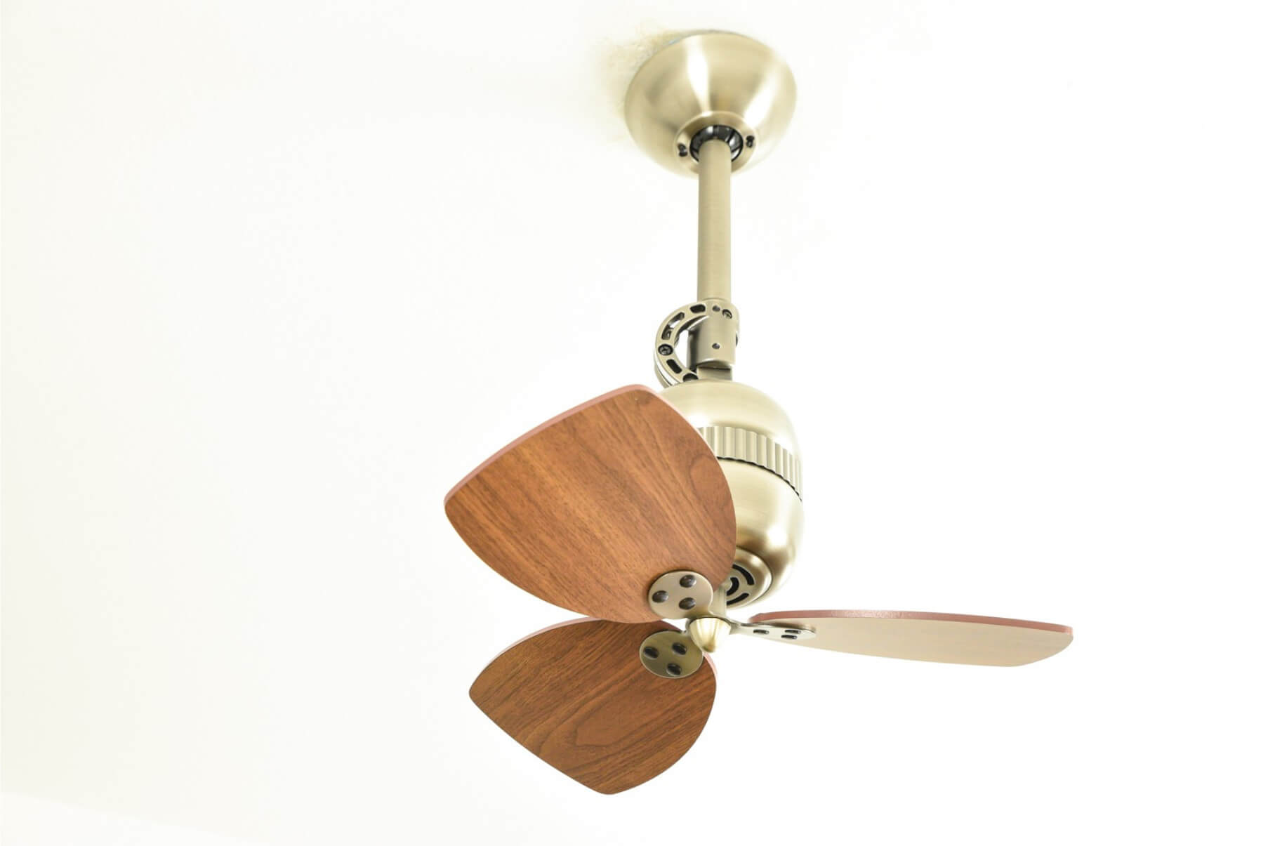 Un piccolo ventilatore da soffitto con pale in legno marrone e dettagli metallici. Il ventilatore è bianco.
