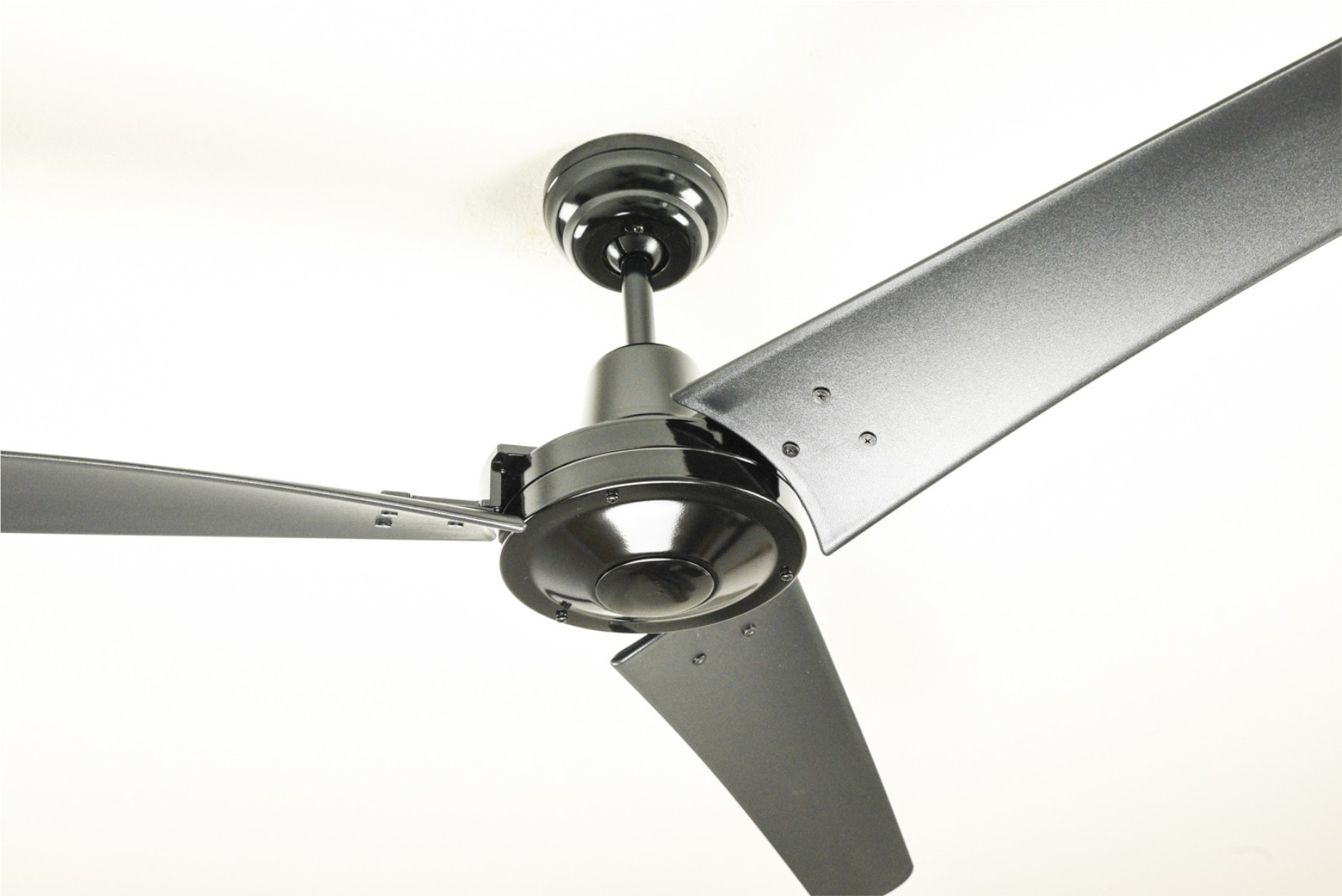 Ein schwarzer Deckenventilator mit drei Flügeln. Weißer Hintergrund.