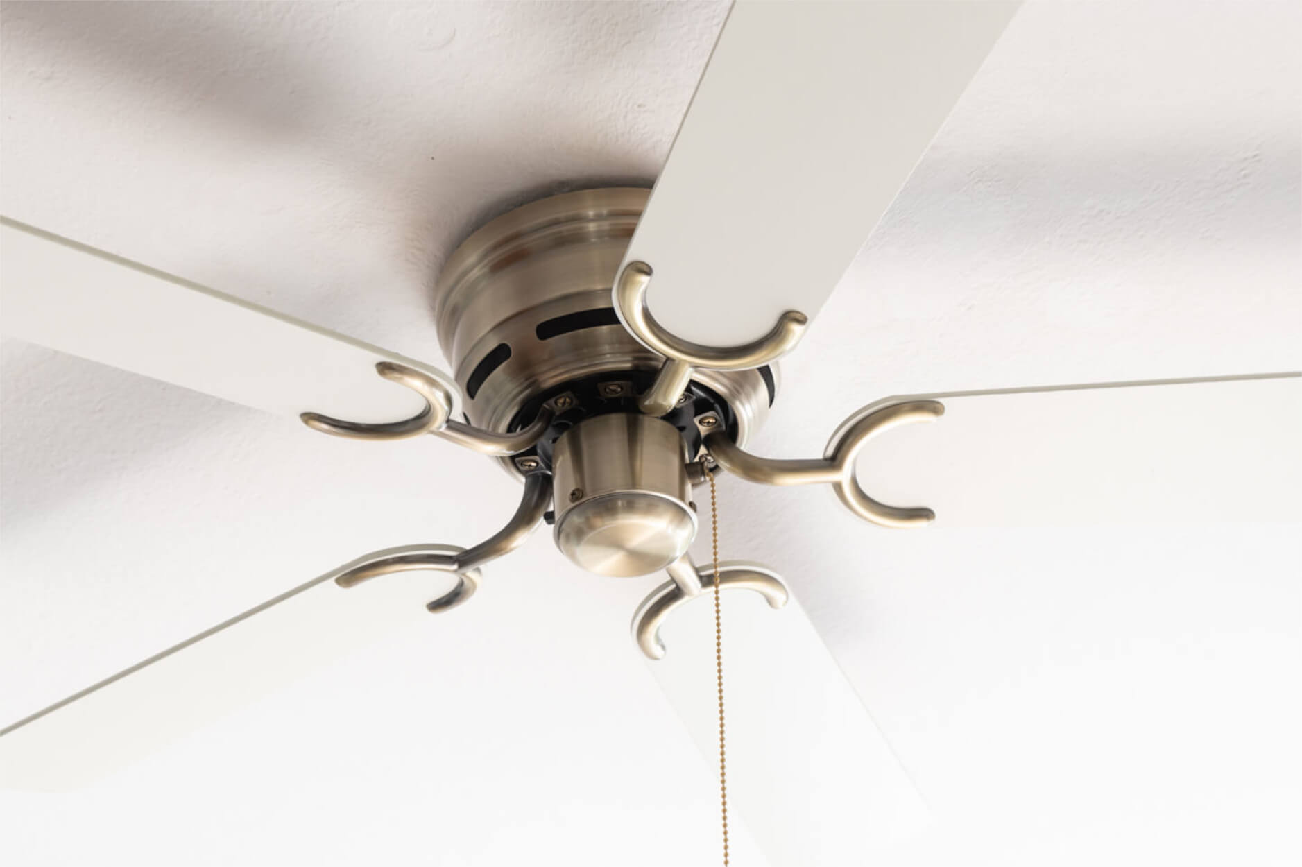 Deckenventilator mit weißen Flügeln und einem Motorgehäuse aus Bronze. Weißer Hintergrund.